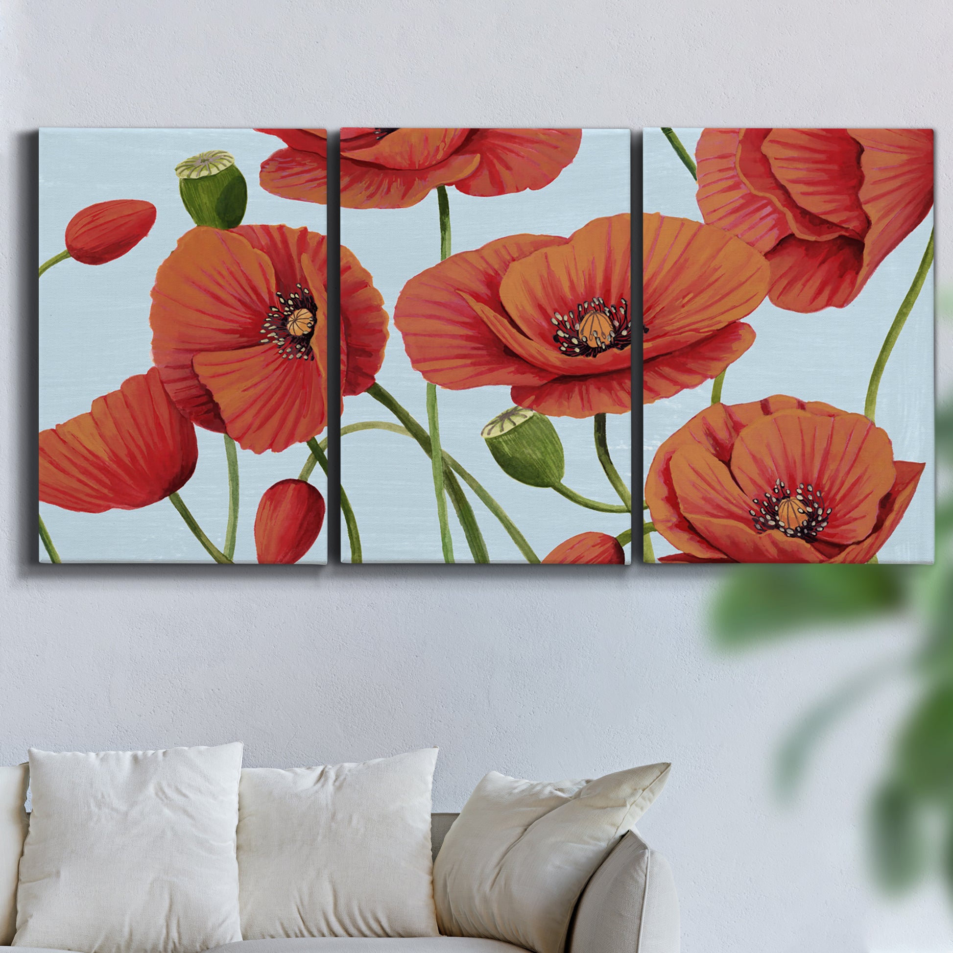 Three-panel canvas wall art featuring red poppies in motion, displayed in a living room above a sofa.