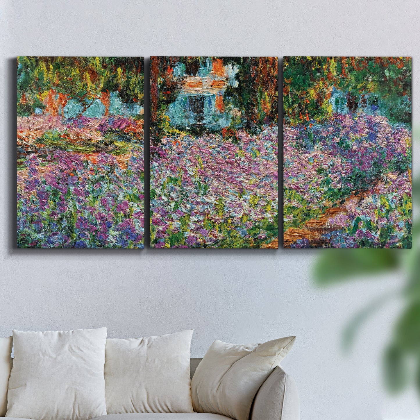 Three-panel canvas wall art featuring blooming irises in garden bed, displayed in a living room above a sofa.