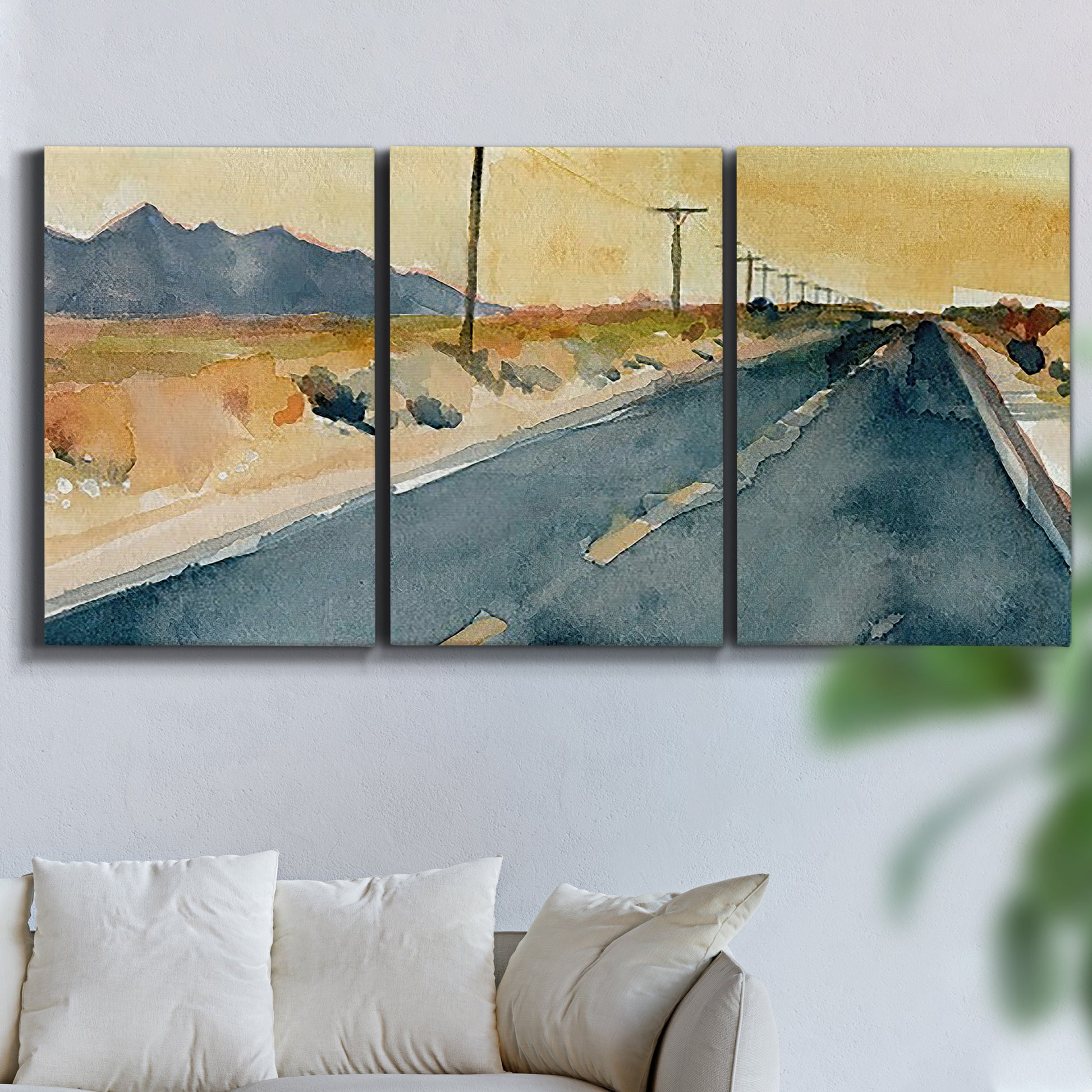Three-panel canvas wall art featuring empty highway stretching through landscape, displayed in a living room above a sofa.