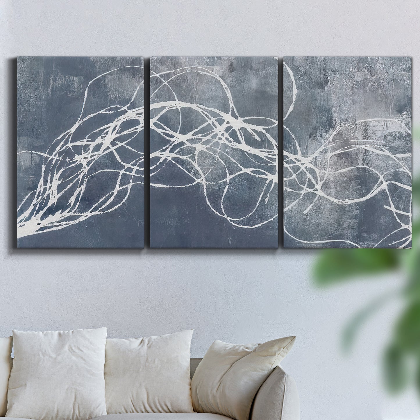Three-panel canvas wall art featuring coastal shoreline at golden hour, displayed in a living room above a sofa.