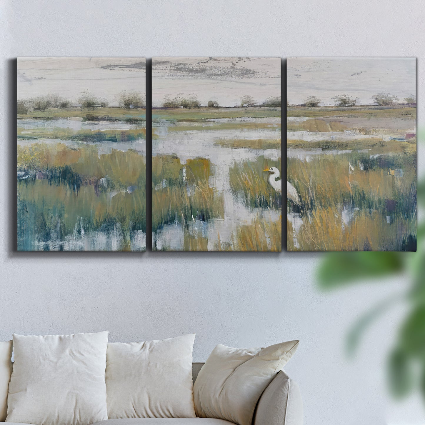 Three-panel canvas wall art featuring pastoral marshland landscape, displayed in a living room above a sofa.