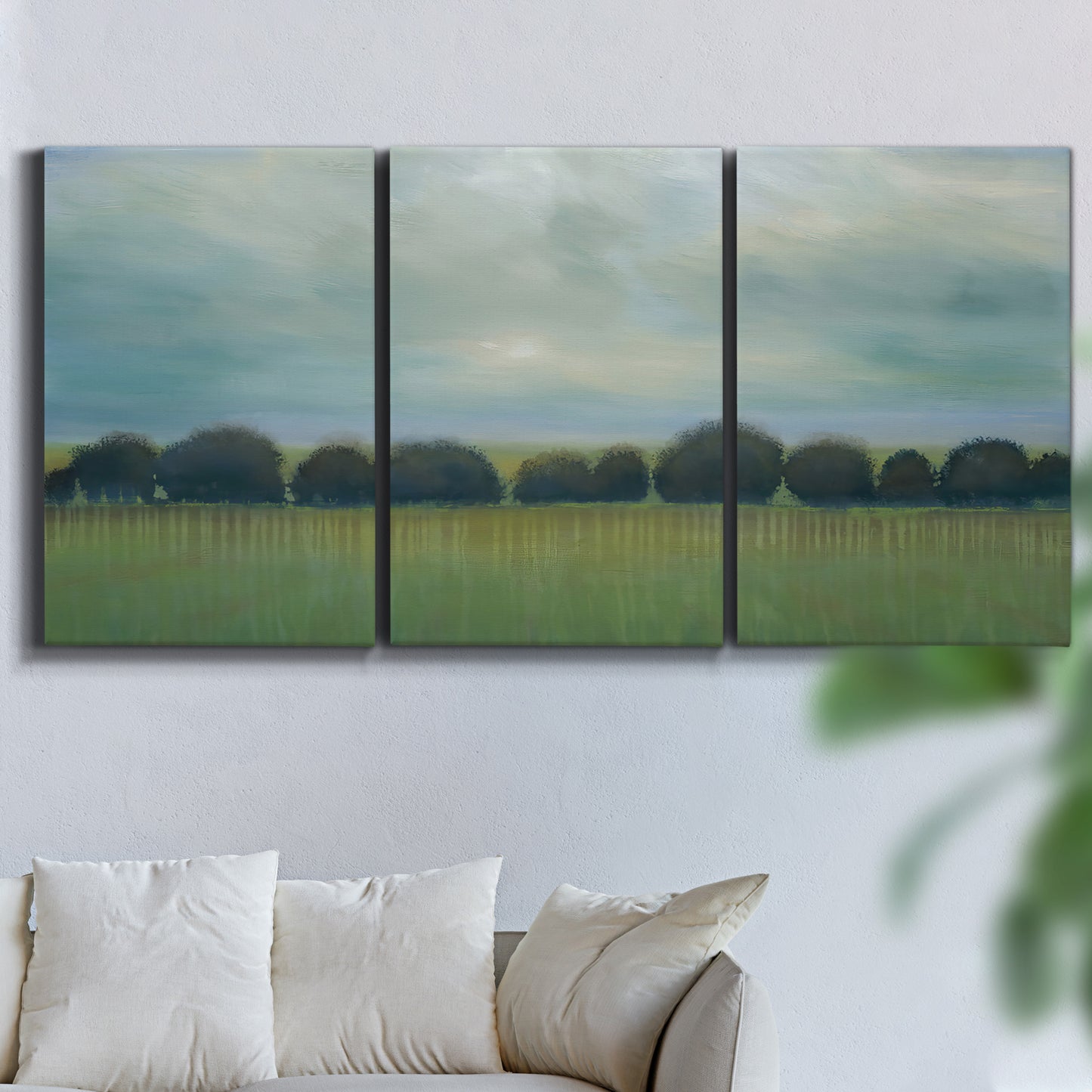 Three-panel canvas wall art featuring rolling green pastoral fields, displayed in a living room above a sofa.