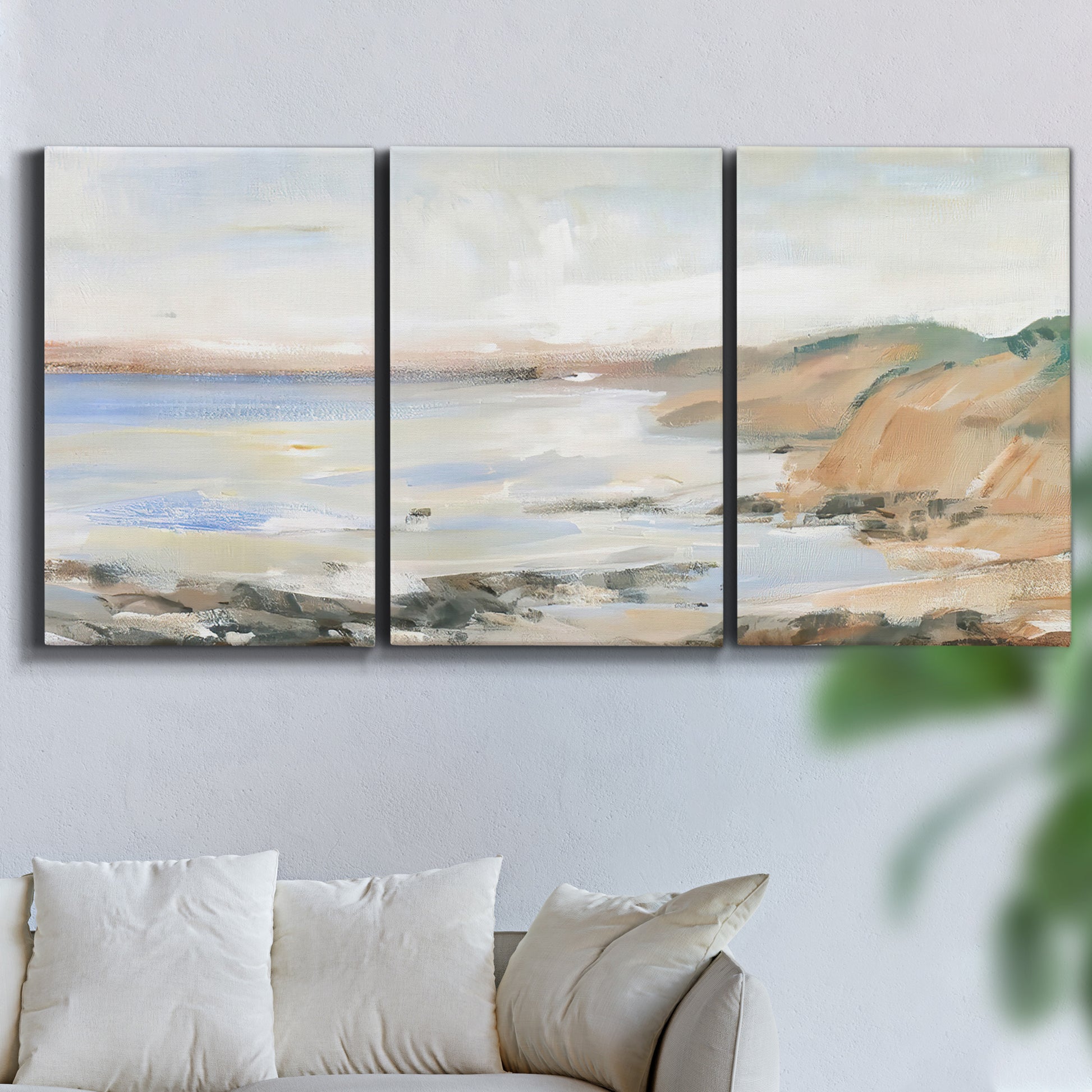 Three-panel canvas wall art featuring coastal shoreline landscape study, displayed in a living room above a sofa.