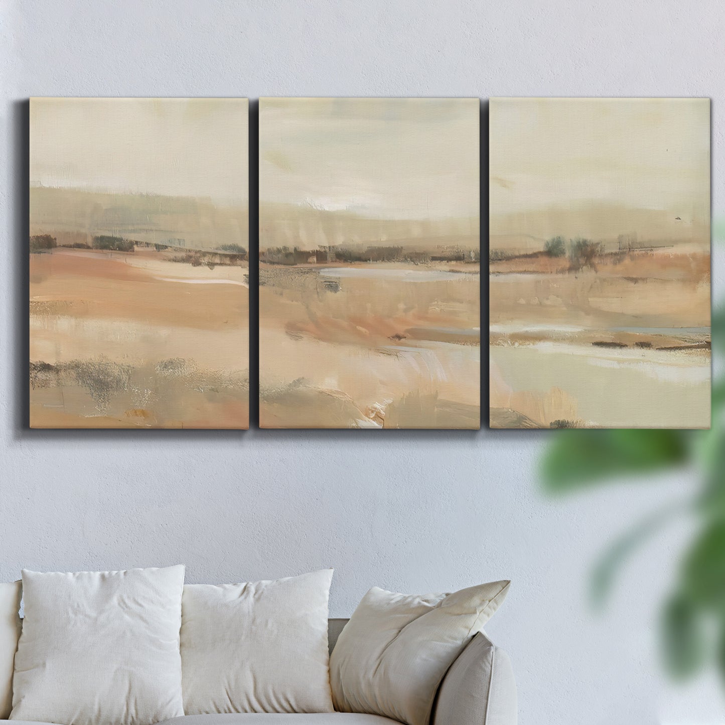 Three-panel canvas wall art featuring earth toned abstract landscape, displayed in a living room above a sofa.