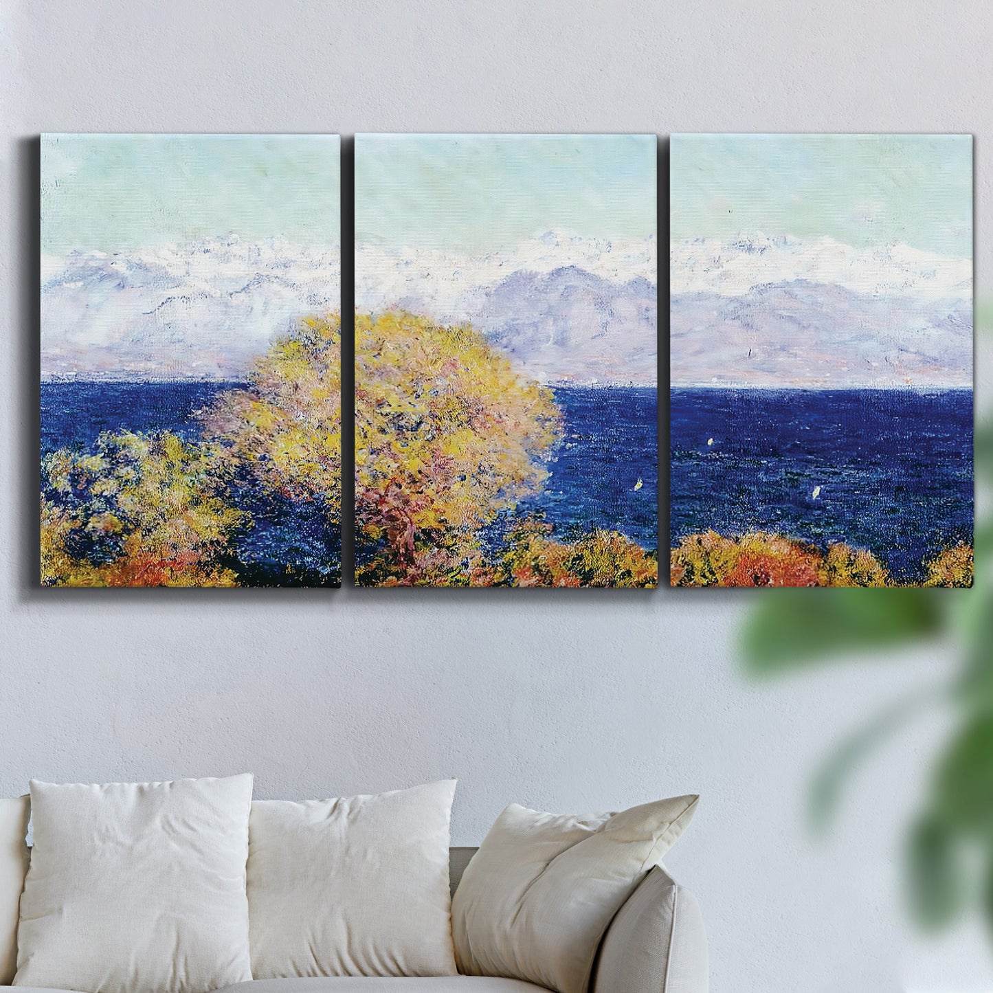 Three-panel canvas wall art featuring mediterranean coastline with headland, displayed in a living room above a sofa.