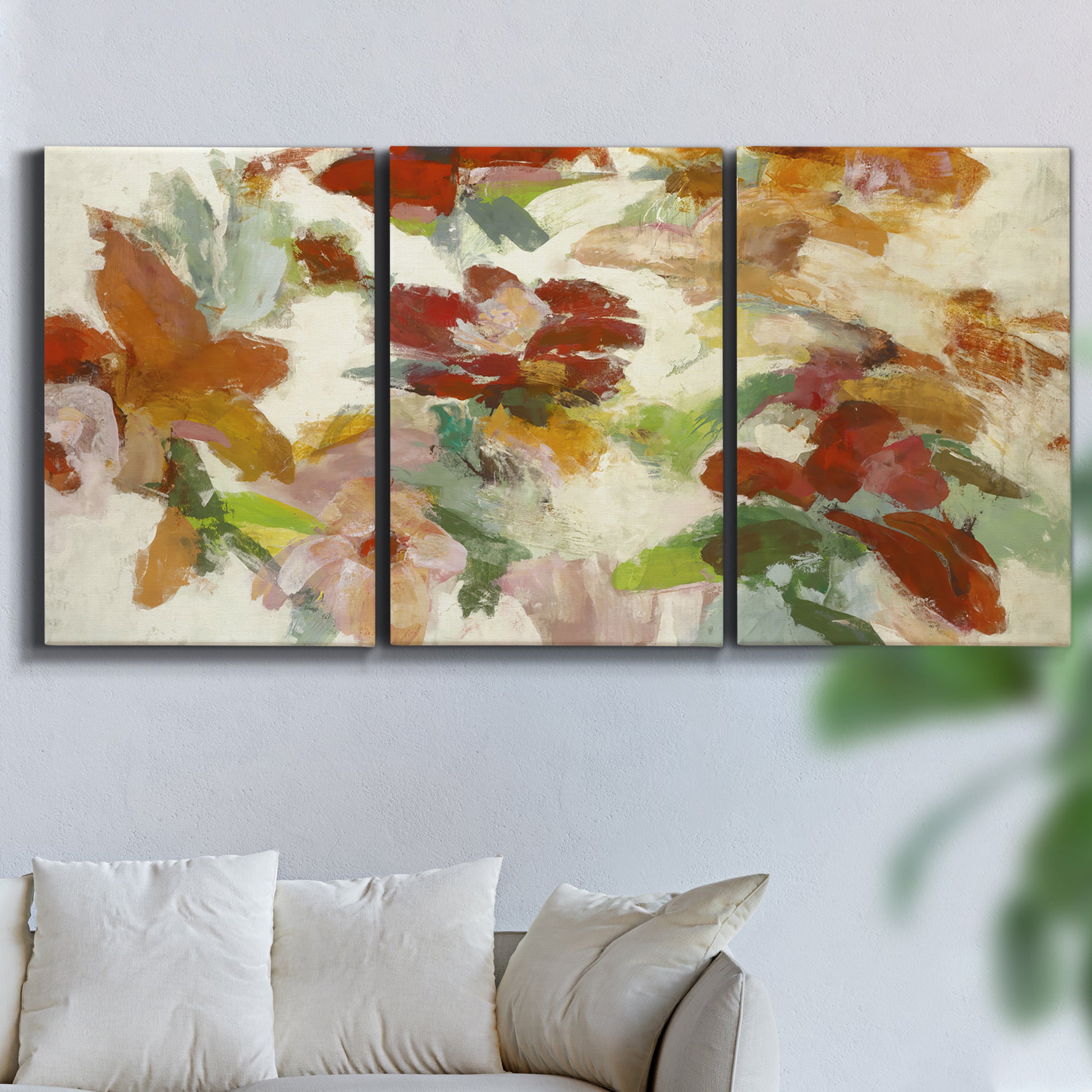Three-panel canvas wall art featuring layered floral botanical impressions, displayed in a living room above a sofa.