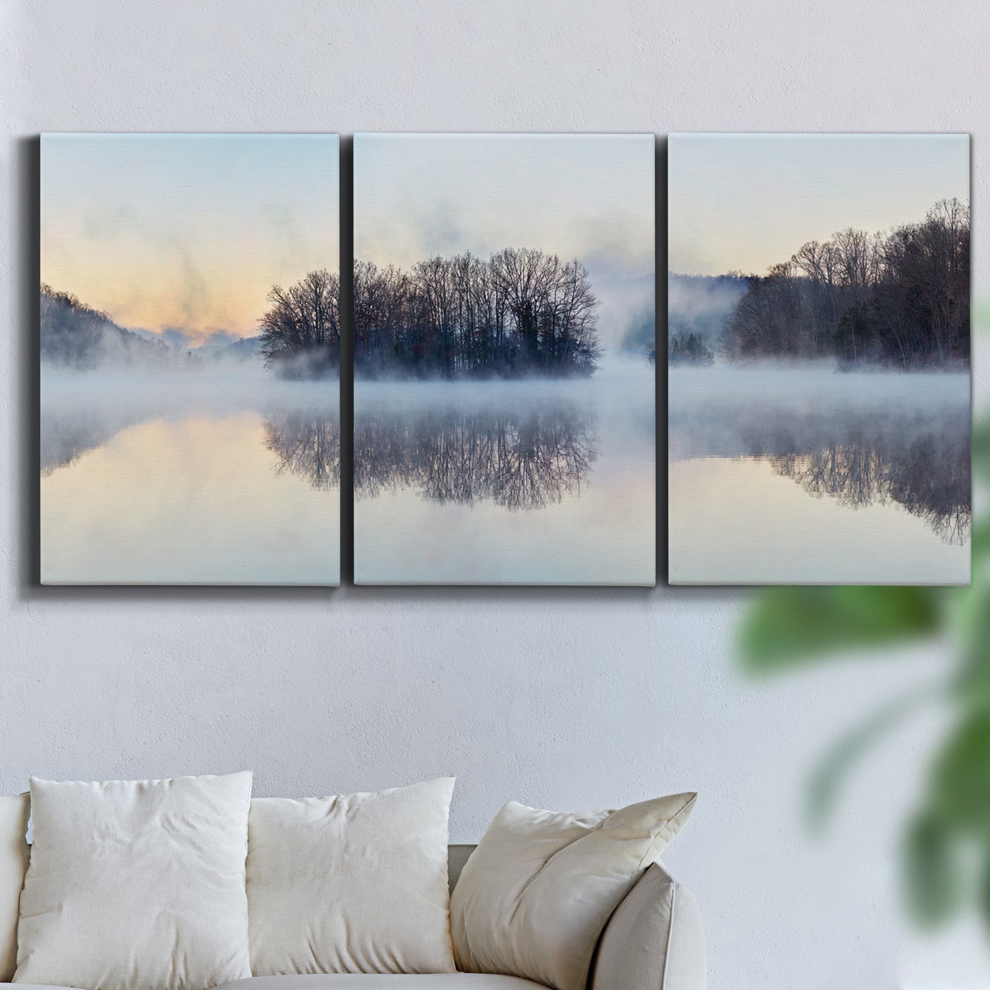 Three-panel canvas wall art featuring misty water landscape photograph, displayed in a living room above a sofa.