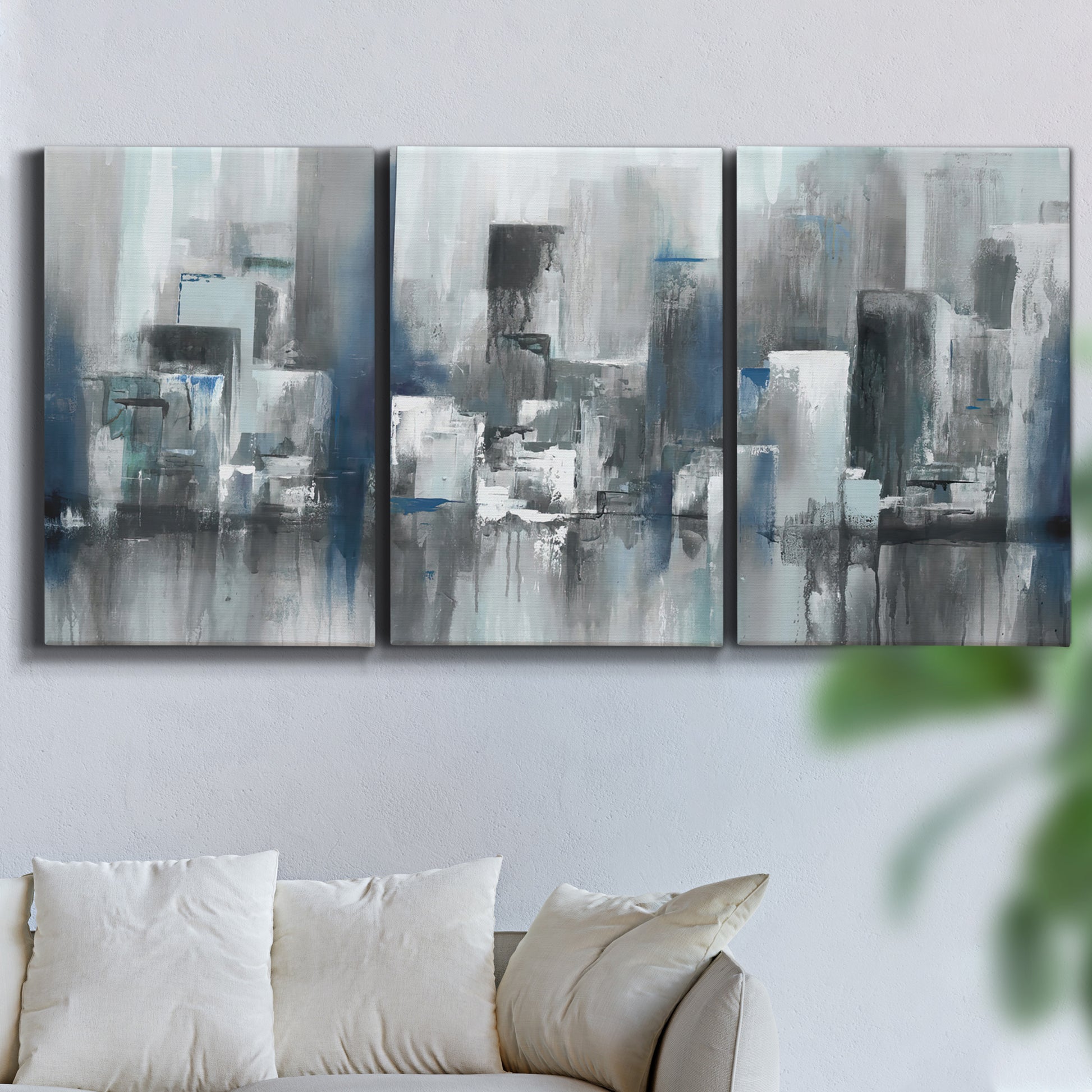 Three-panel canvas wall art featuring urban cityscape rendered in blue tones, displayed in a living room above a sofa.