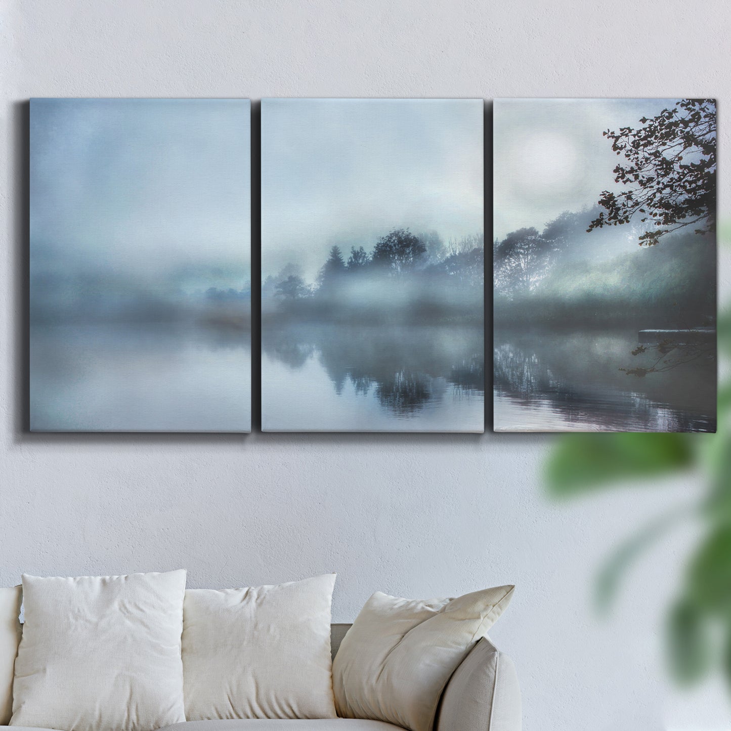 Three-panel canvas wall art featuring calm waters at sunrise photograph, displayed in a living room above a sofa.