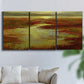 Three-panel canvas wall art featuring coastal shoreline with warm light, displayed in a living room above a sofa.