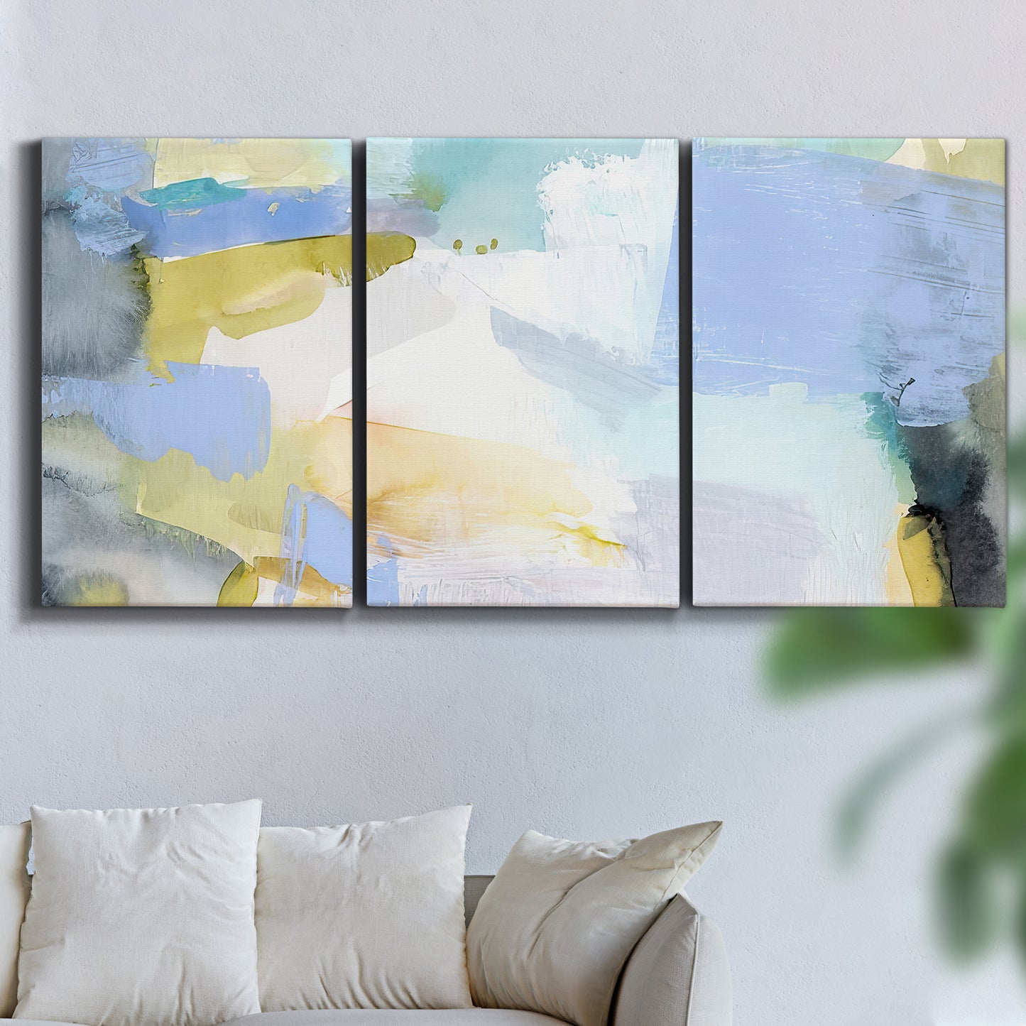 Three-panel canvas wall art featuring soft abstract spring watercolor tones, displayed in a living room above a sofa.
