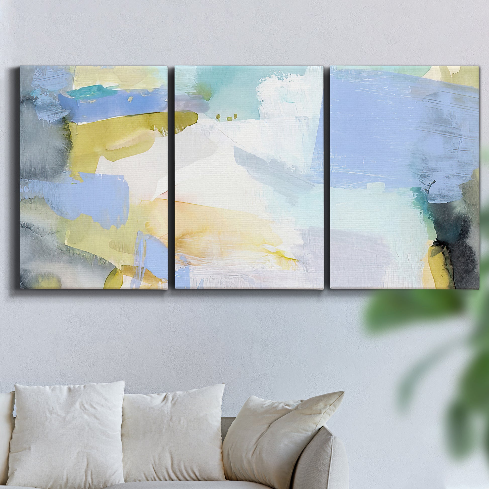 Three-panel canvas wall art featuring soft abstract spring watercolor tones, displayed in a living room above a sofa.