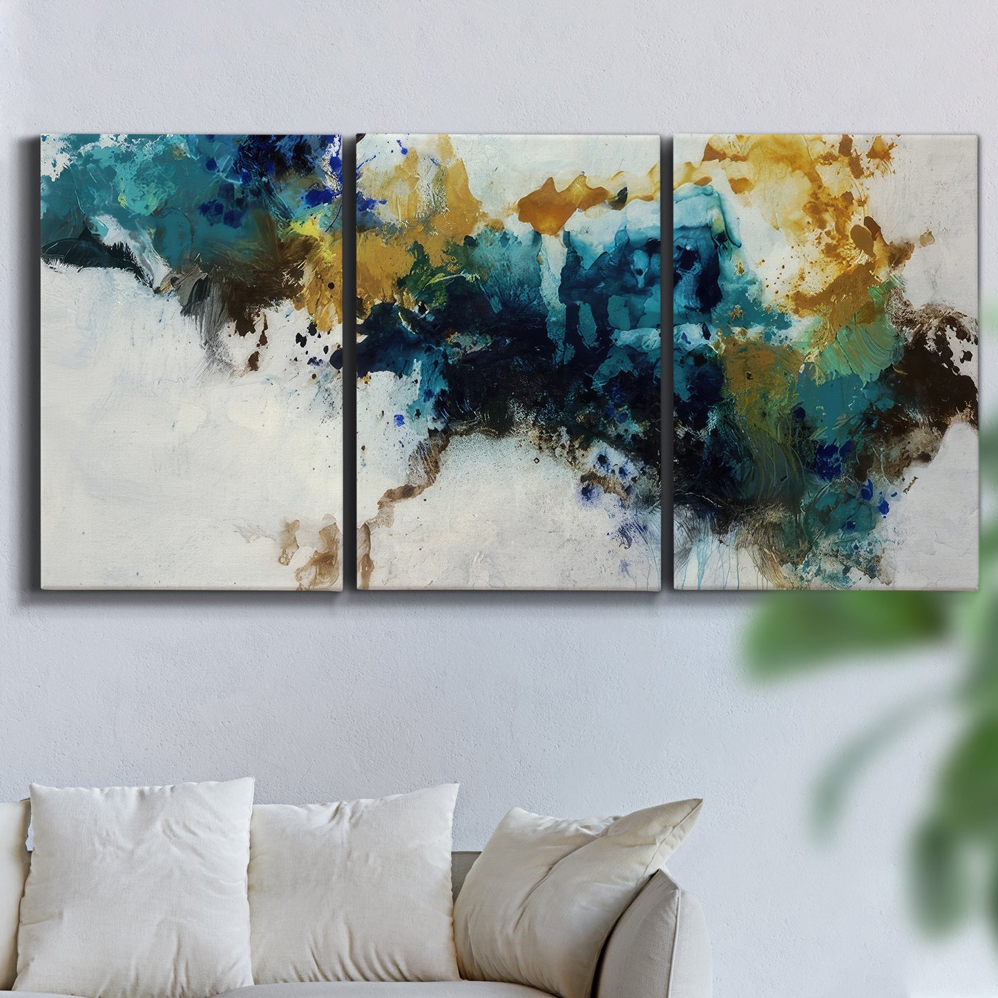 Three-panel canvas wall art featuring teal abstract paint splatter, displayed in a living room above a sofa.