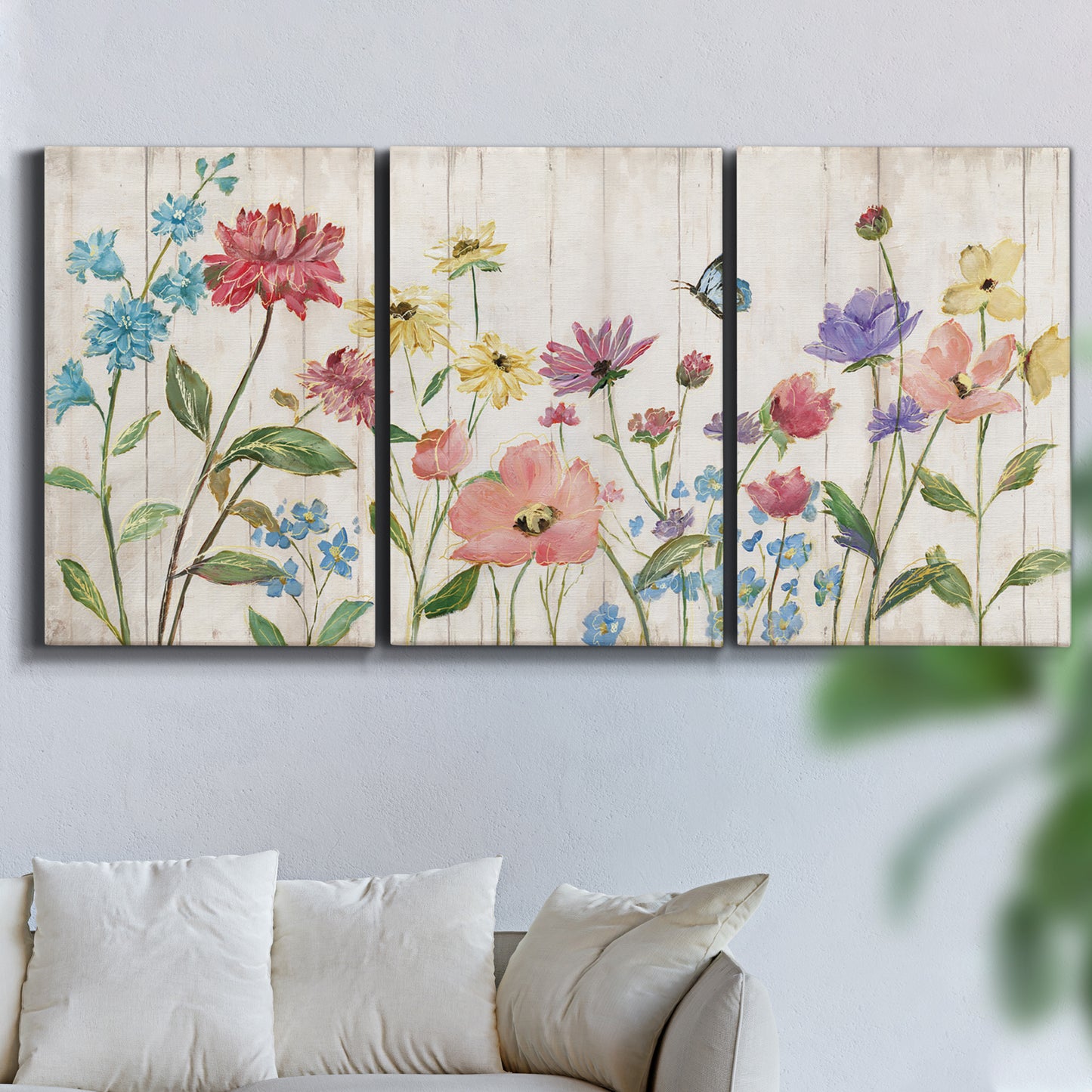 Three-panel canvas wall art featuring delicate wildflower illustration, displayed in a living room above a sofa.