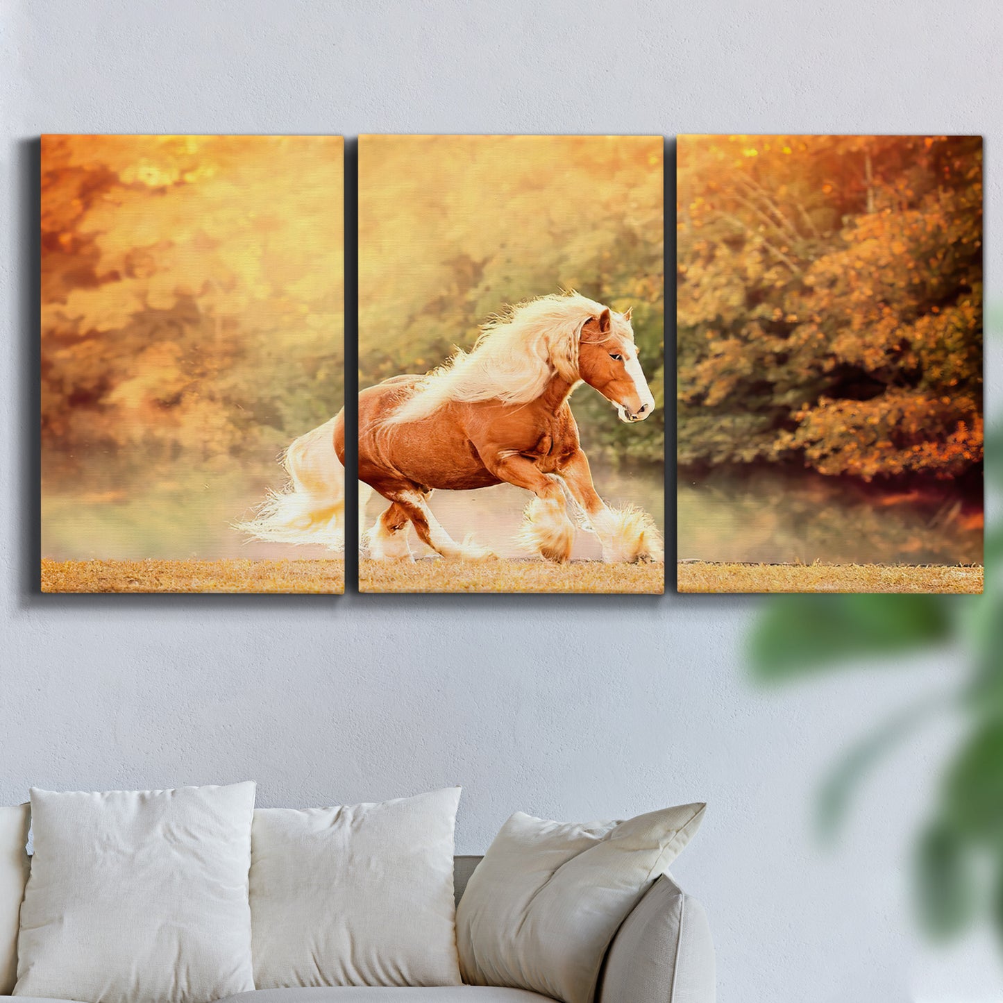 Three-panel canvas wall art featuring running horses captured in motion, displayed in a living room above a sofa.