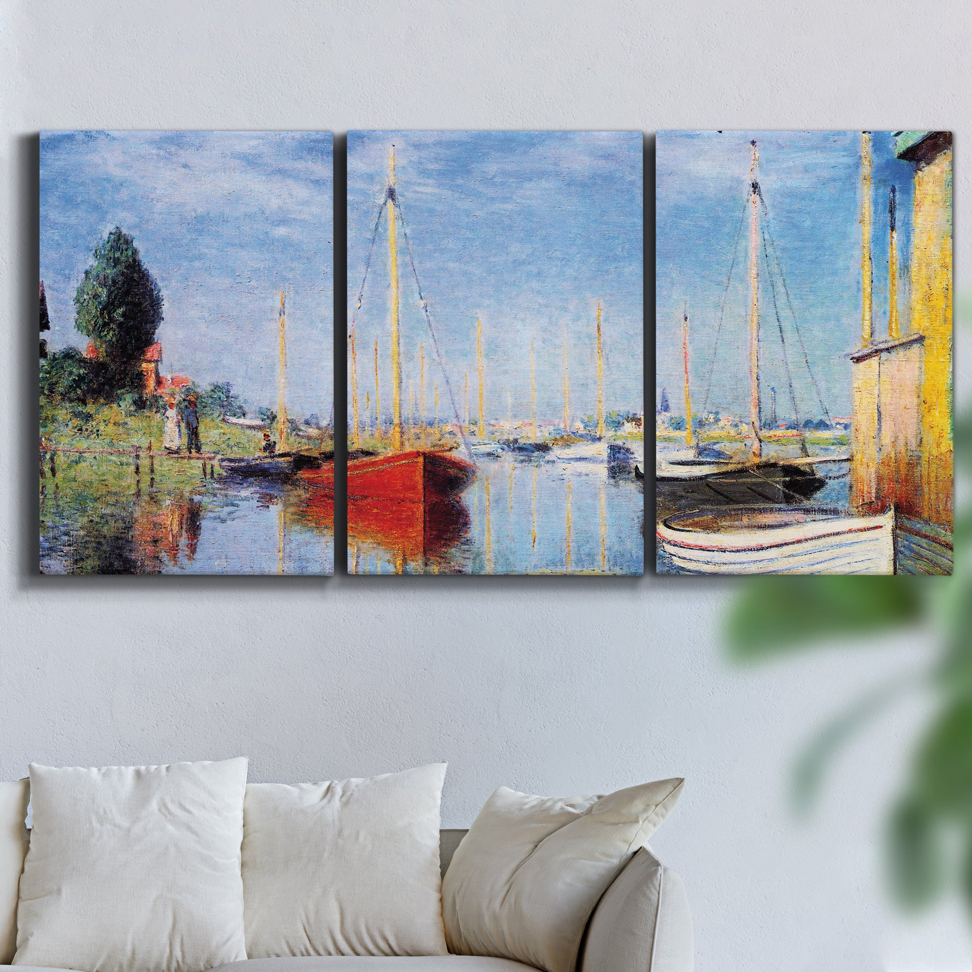 Three-panel canvas wall art featuring sailboats gathered along river, displayed in a living room above a sofa.