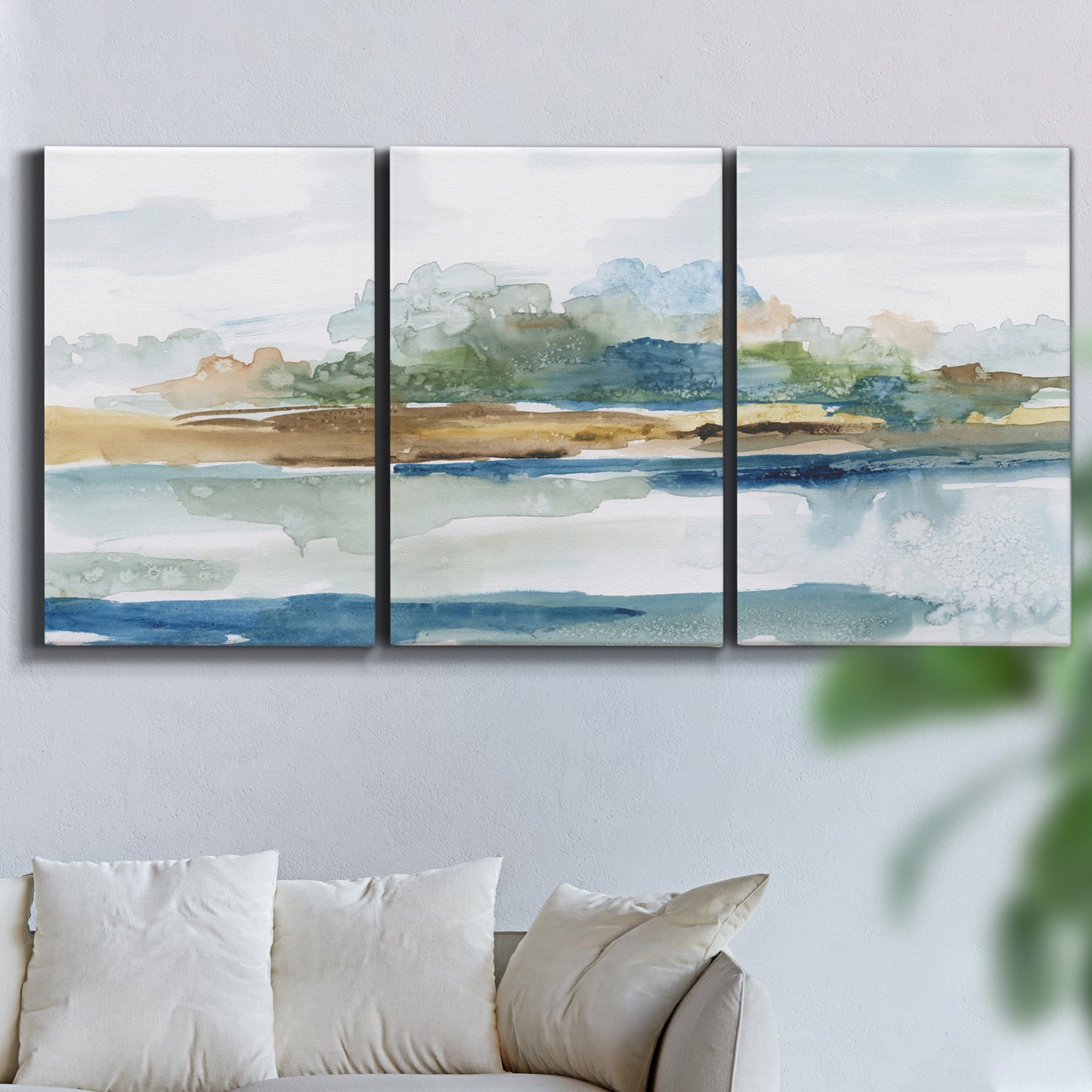 Three-panel canvas wall art featuring flowing blue abstract watercolor, displayed in a living room above a sofa.
