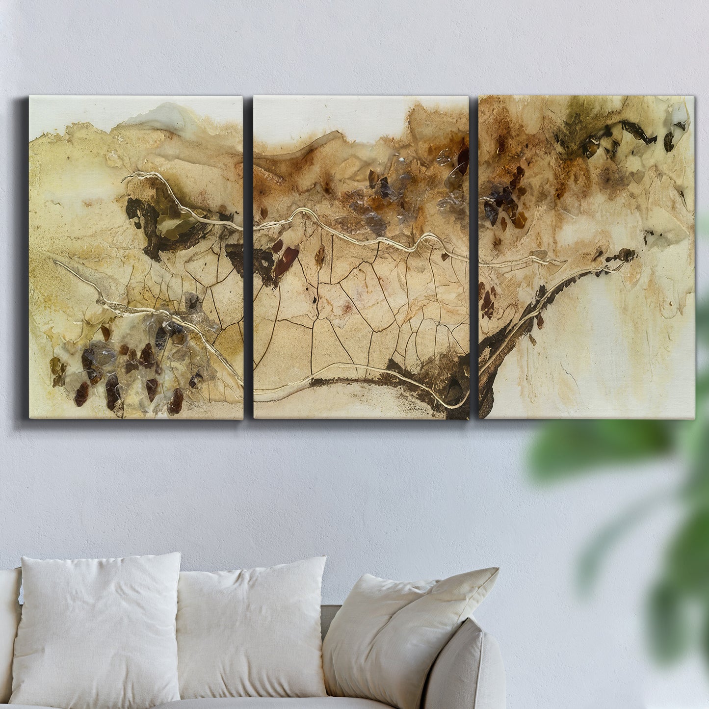 Three-panel canvas wall art featuring muted abstract with metallic gold accents, displayed in a living room above a sofa.