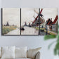 Three-panel canvas wall art featuring windmills beside calm water, displayed in a living room above a sofa.