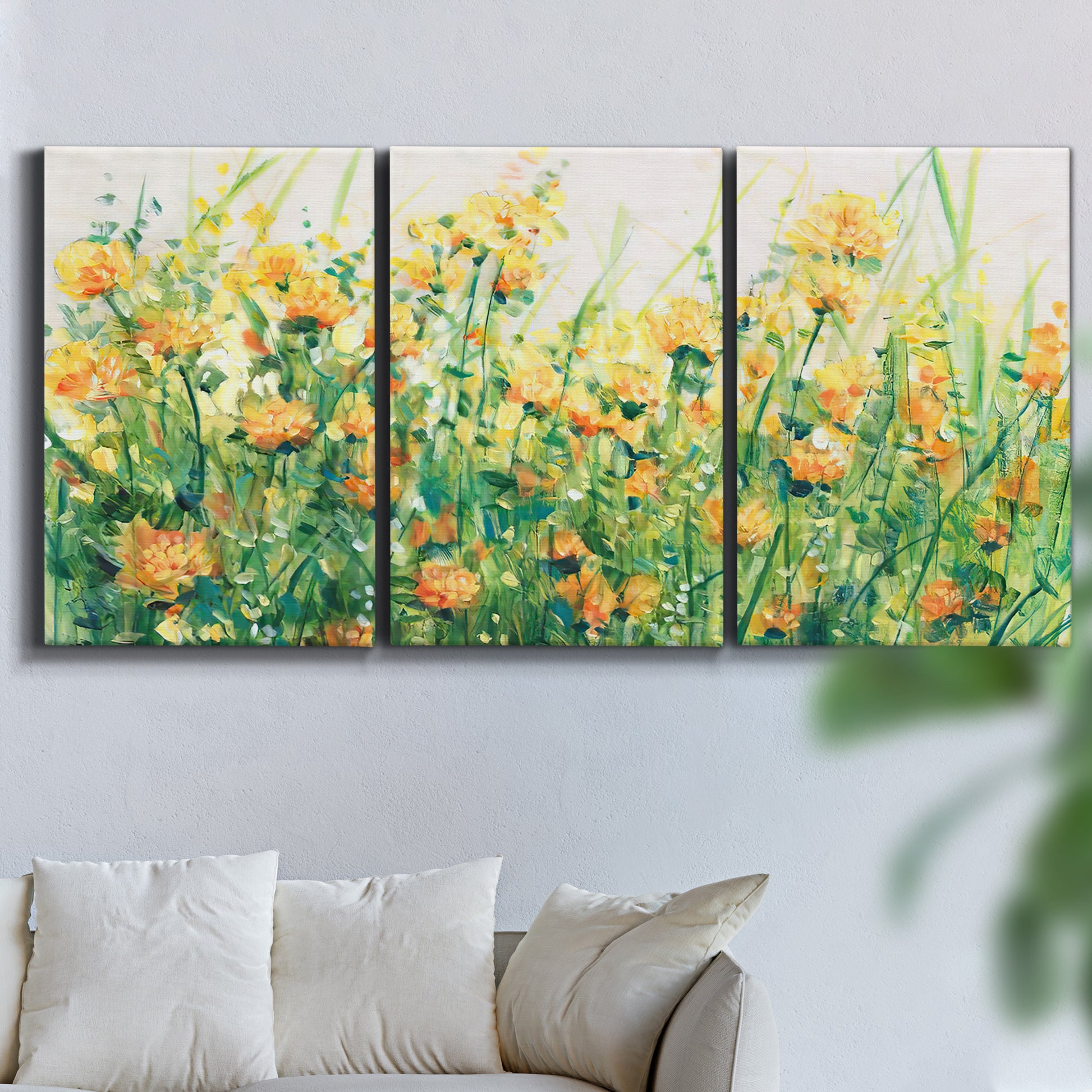 Three-panel canvas wall art featuring colorful garden flowers in bloom, displayed in a living room above a sofa.