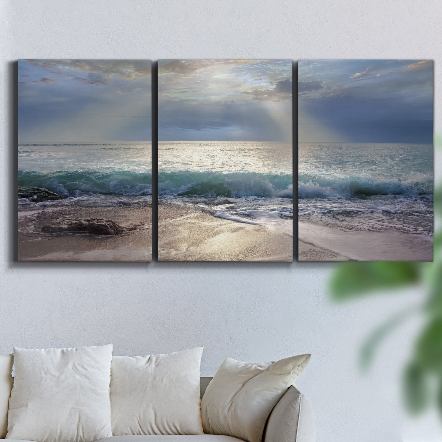Three-panel canvas wall art featuring soft sunrise over open water, displayed in a living room above a sofa.