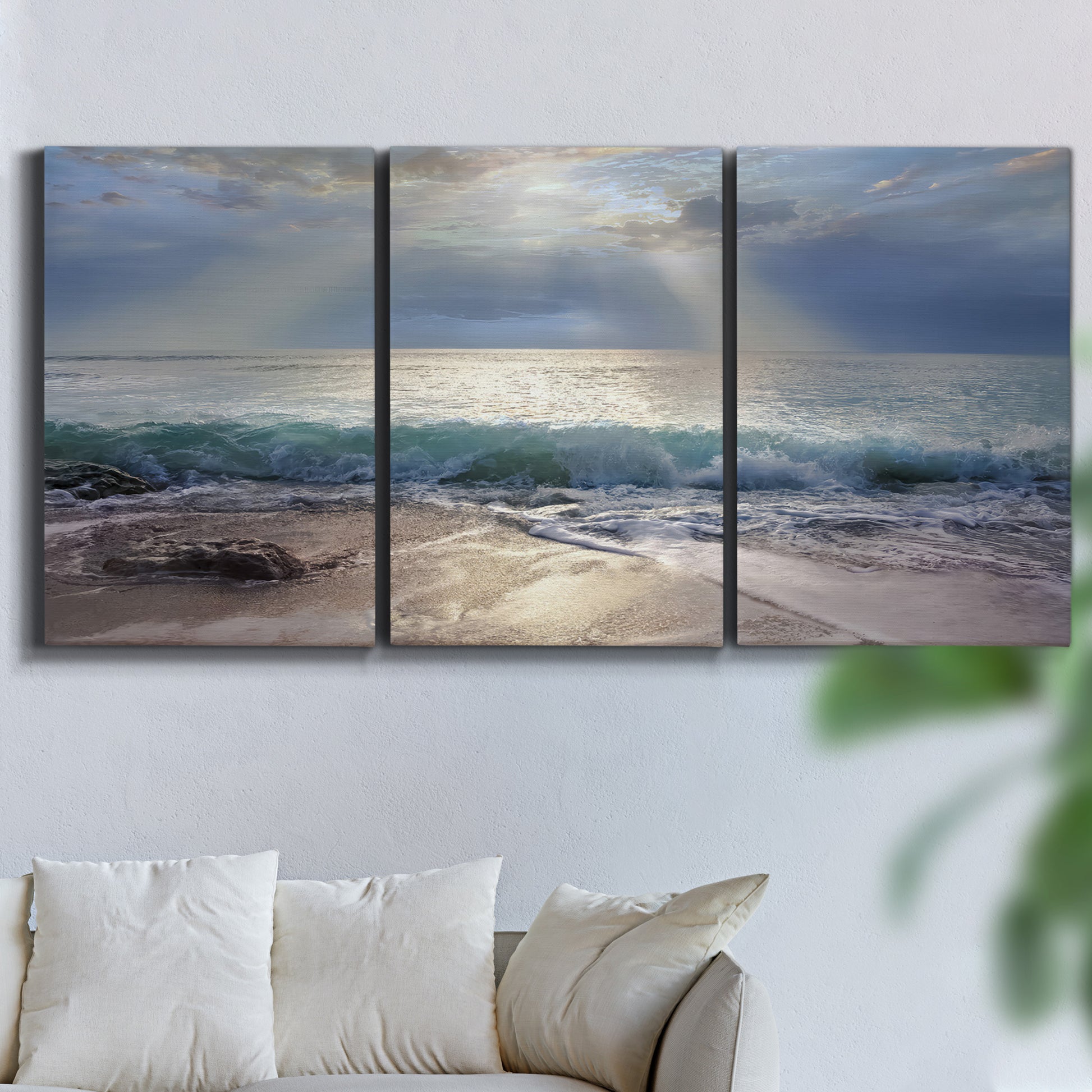 Three-panel canvas wall art featuring soft sunrise over open water, displayed in a living room above a sofa.