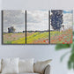 Three-panel canvas wall art featuring open poppy field in countryside, displayed in a living room above a sofa.
