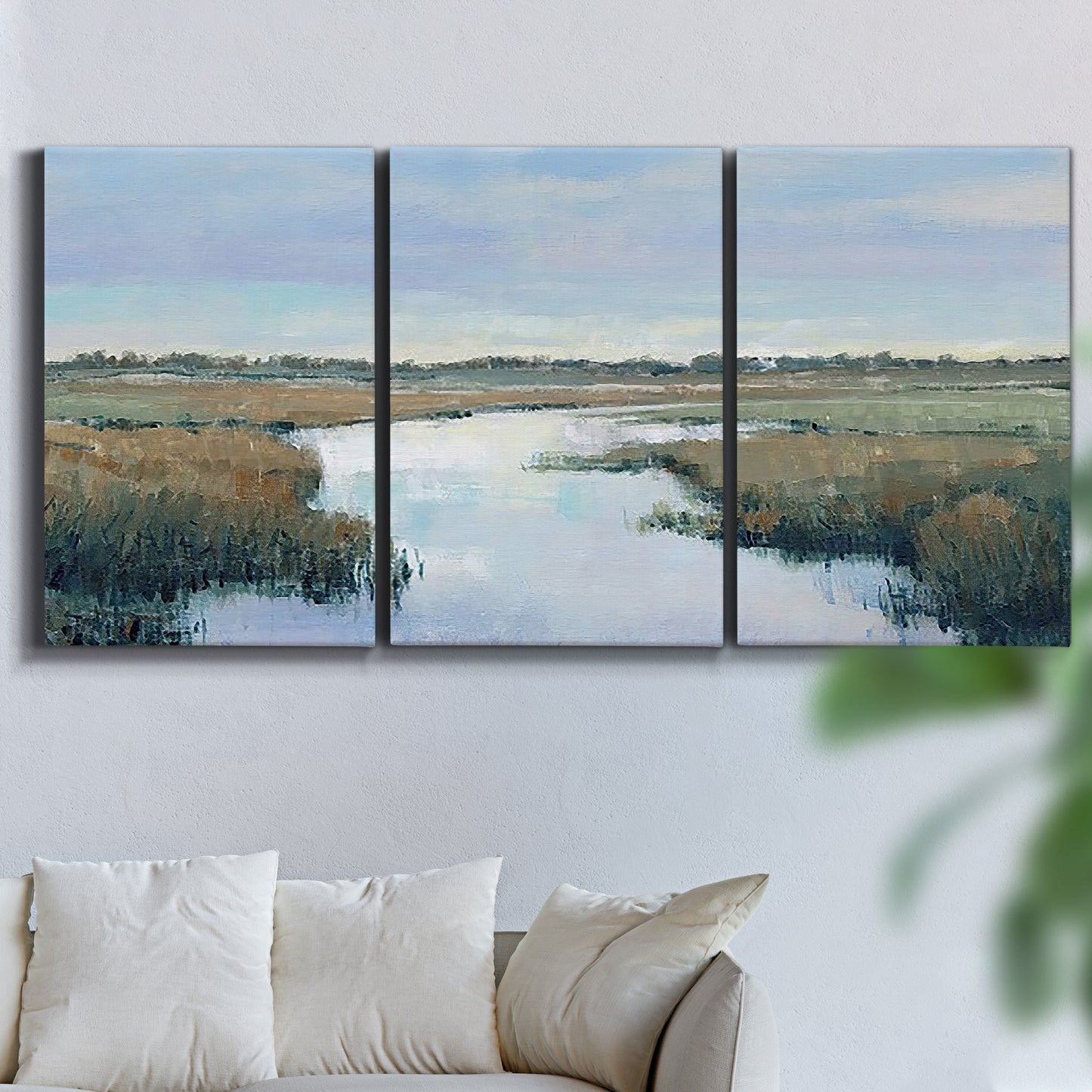 Three-panel canvas wall art featuring coastal plain with layered horizon, displayed in a living room above a sofa.