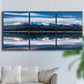 Three-panel canvas wall art featuring calm lake beneath mountains photograph, displayed in a living room above a sofa.