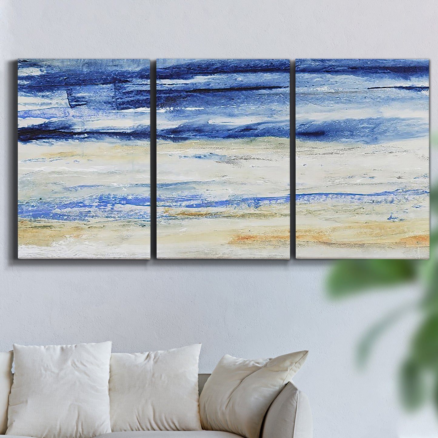 Three-panel canvas wall art featuring turbulent abstract ocean wave motion, displayed in a living room above a sofa.