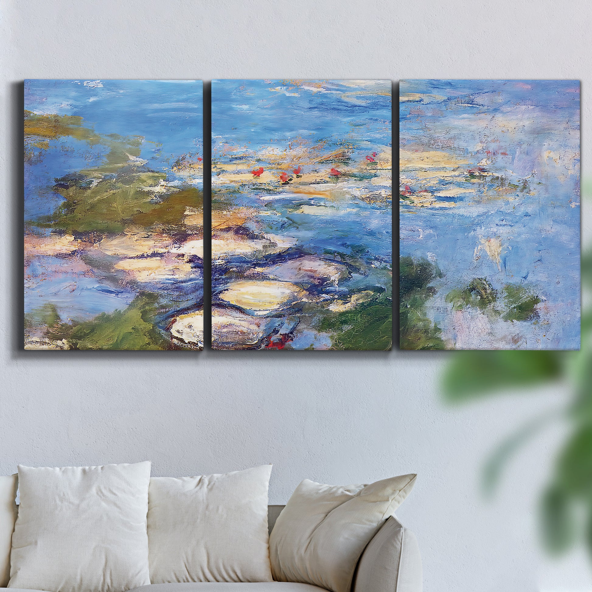 Three-panel canvas wall art featuring water lilies in blue and gold, displayed in a living room above a sofa.