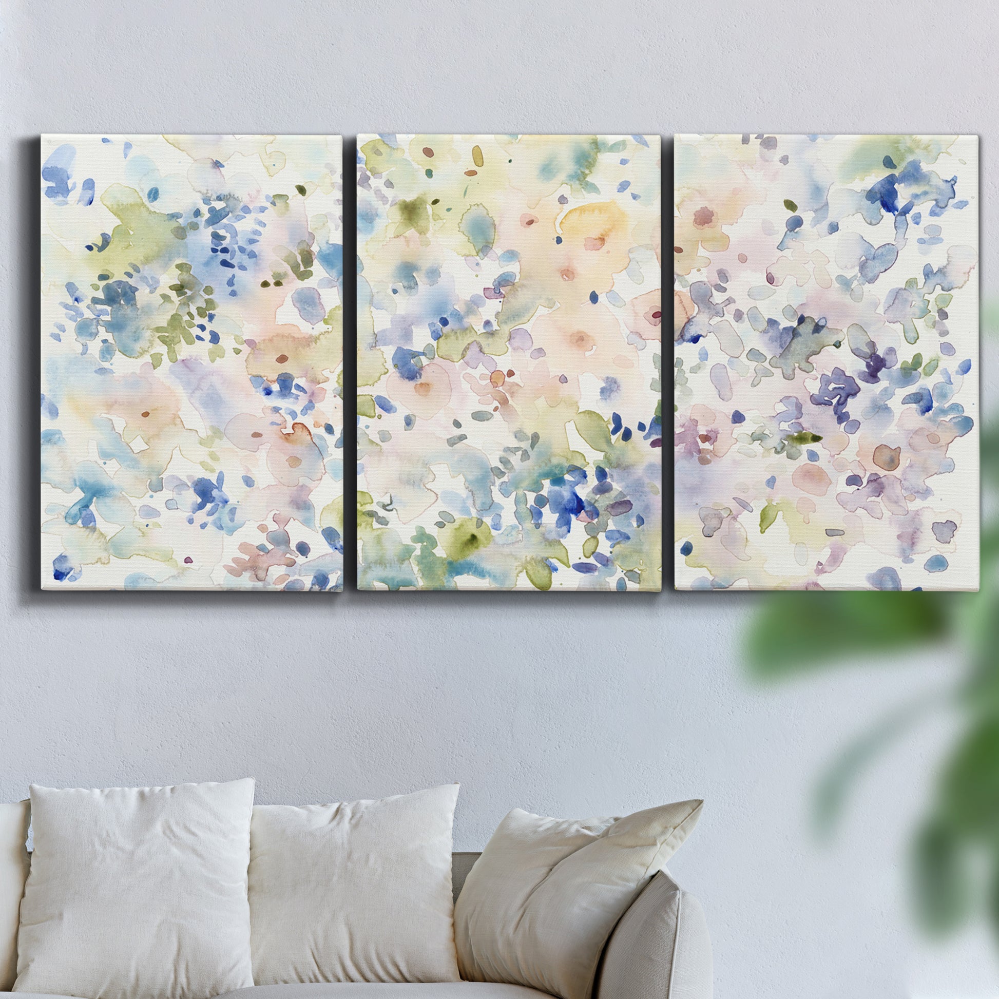 Three-panel canvas wall art featuring flowing abstract watercolor, displayed in a living room above a sofa.