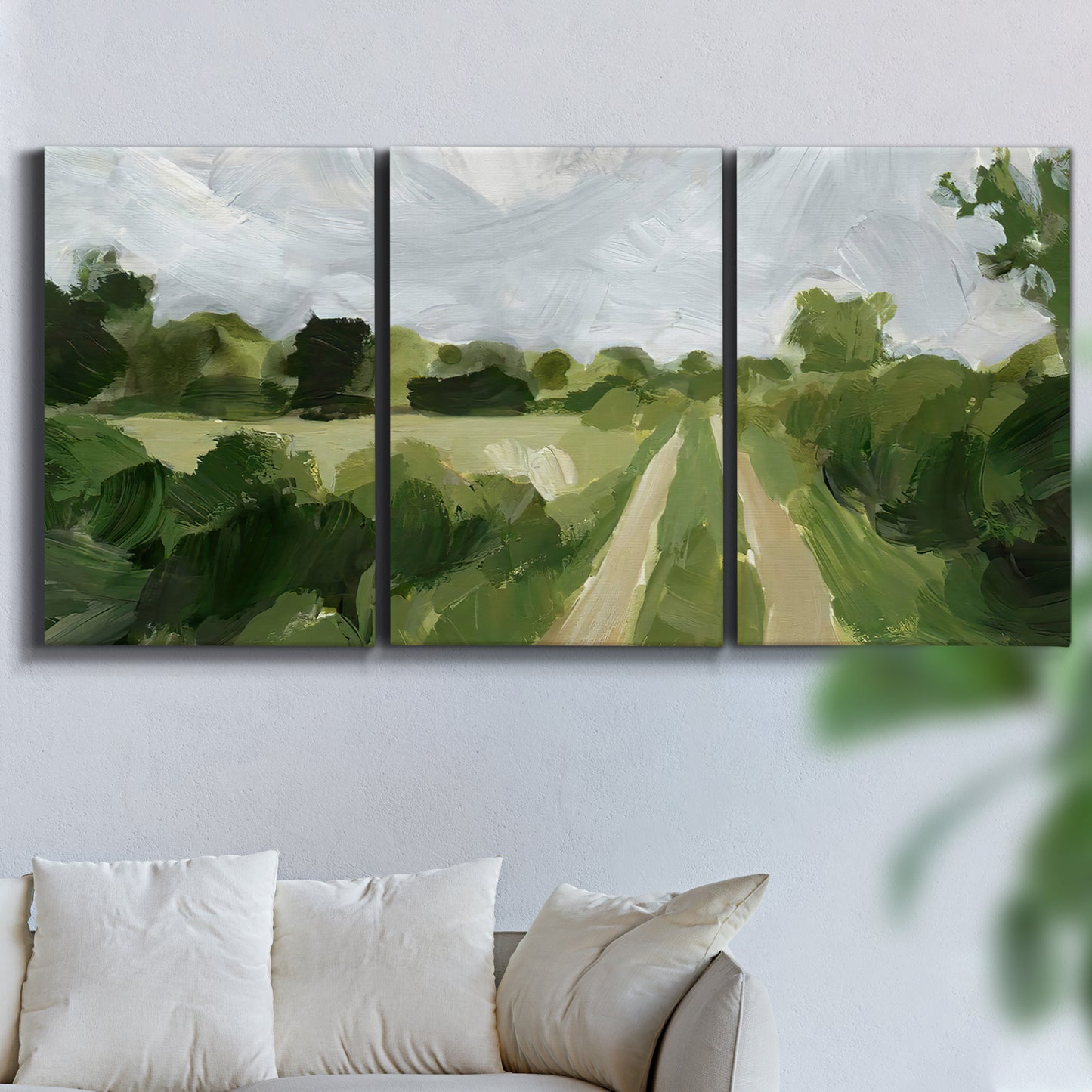 Three-panel canvas wall art featuring meadow trail through open grassland, displayed in a living room above a sofa.