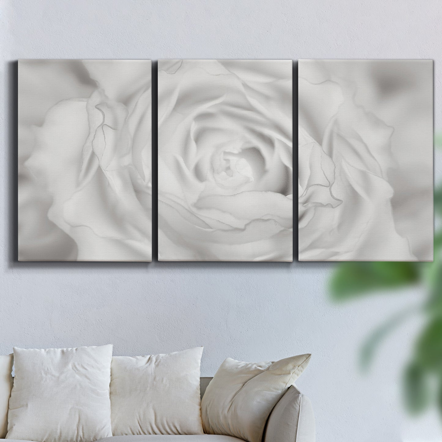 Three-panel canvas wall art featuring monochrome rose study photograph, displayed in a living room above a sofa.