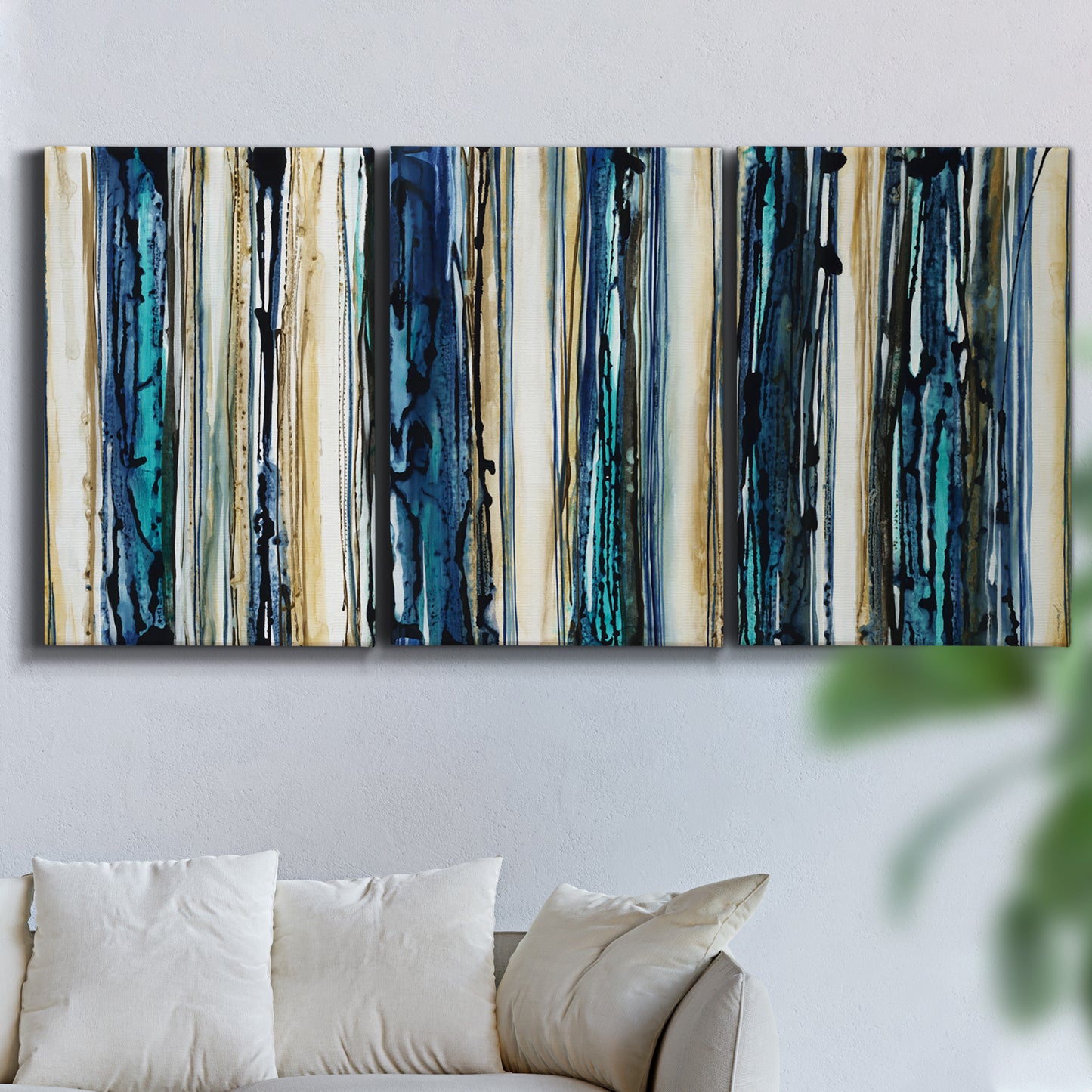 Three-panel canvas wall art featuring vertical blue abstract streaks, displayed in a living room above a sofa.