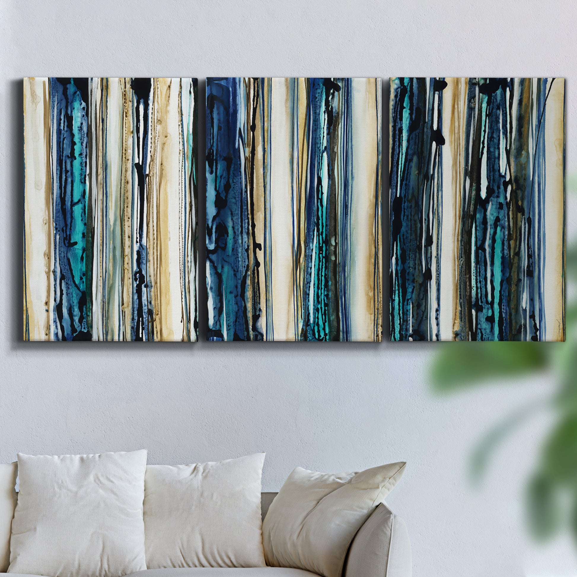Three-panel canvas wall art featuring vertical blue abstract streaks, displayed in a living room above a sofa.