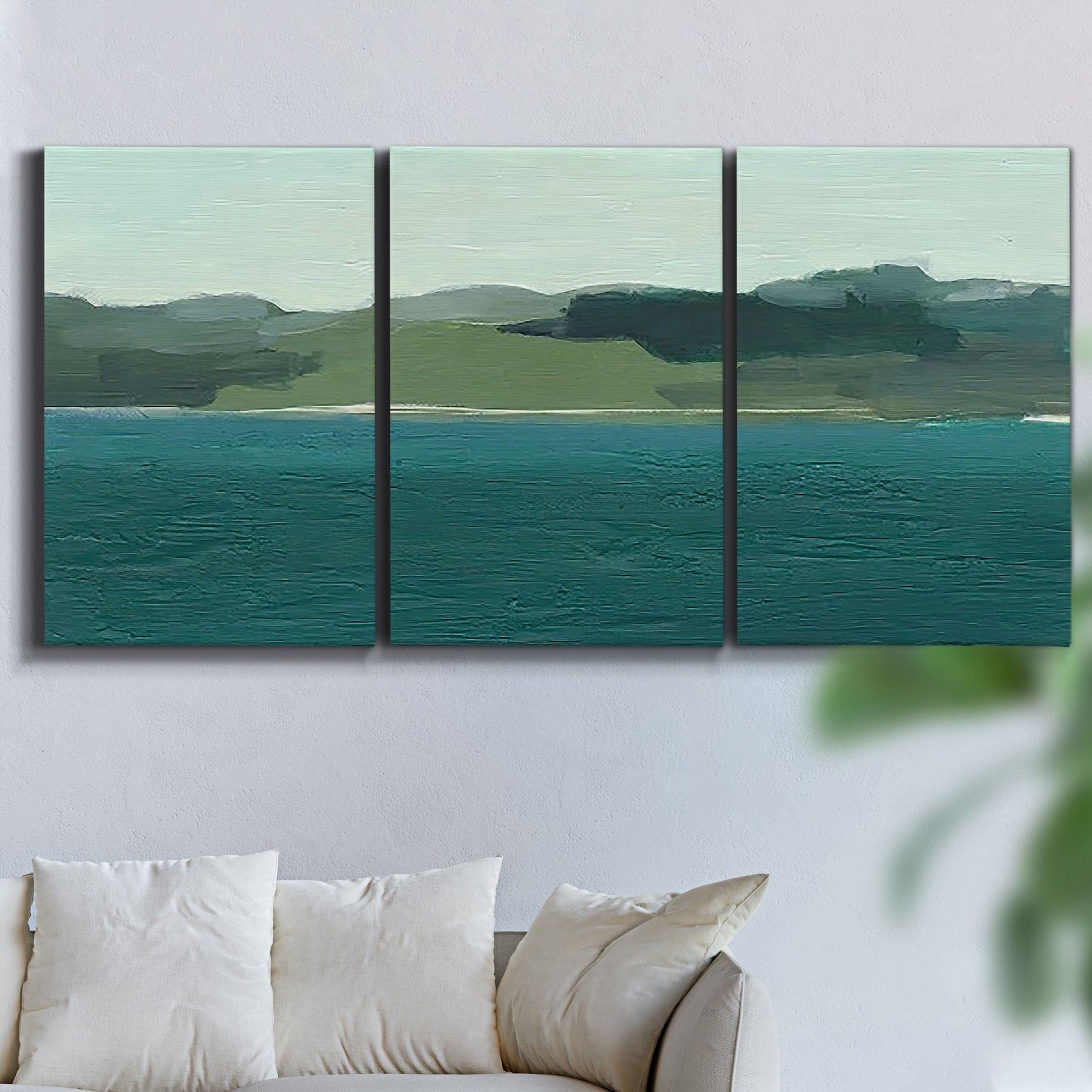 Three-panel canvas wall art featuring calm lake water under open sky, displayed in a living room above a sofa.