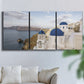 Three-panel canvas wall art featuring white buildings overlooking sea cliffs, displayed in a living room above a sofa.