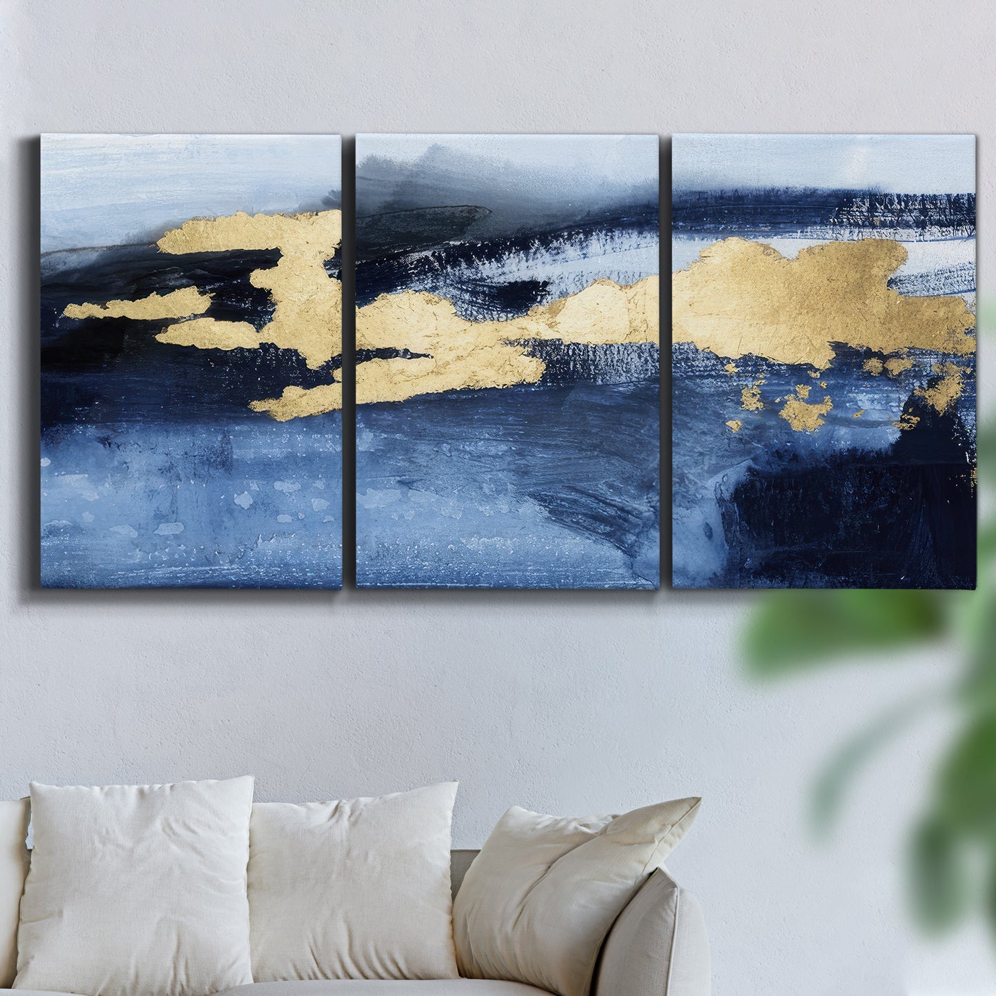 Three-panel canvas wall art featuring coastal shoreline with warm light, displayed in a living room above a sofa.
