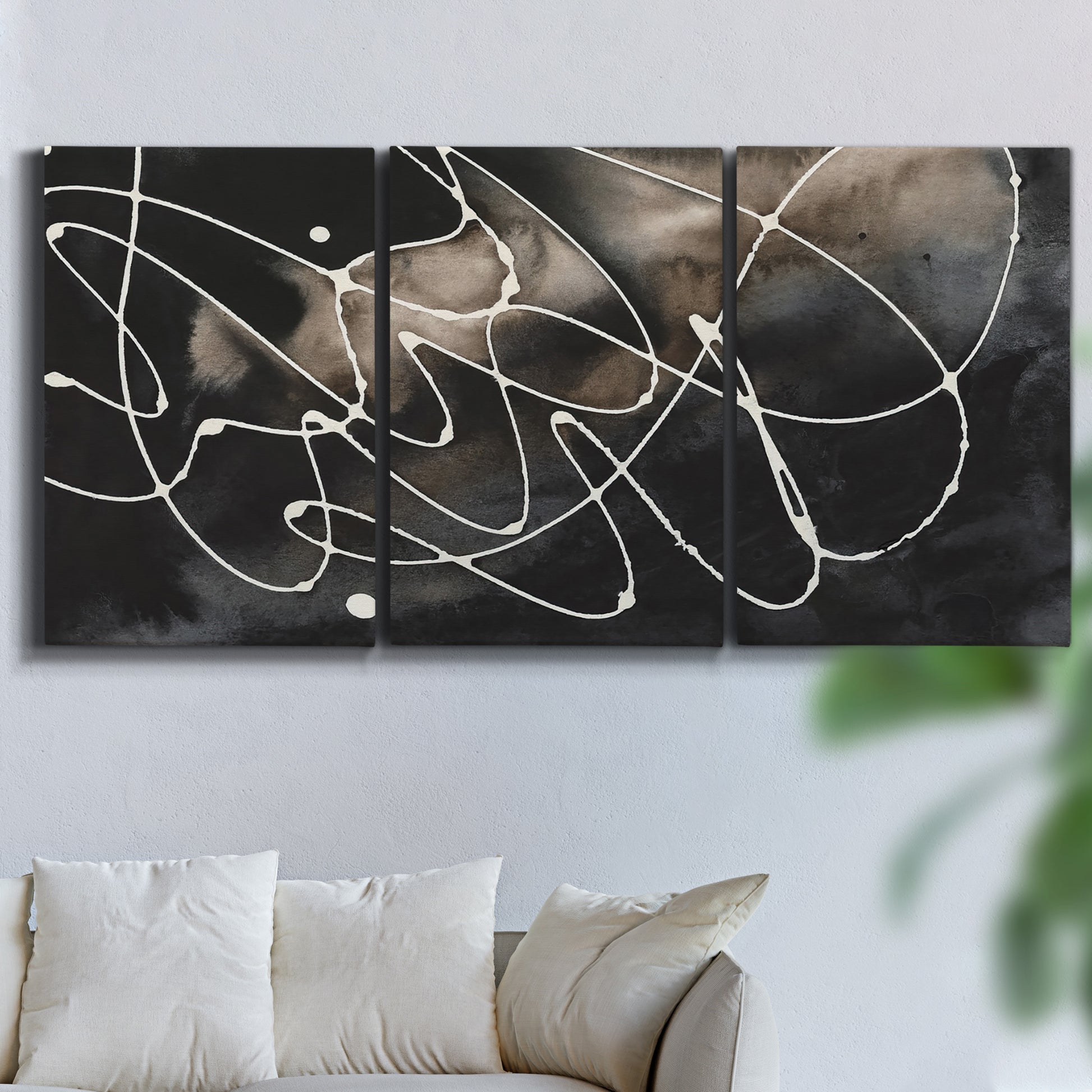 Three-panel canvas wall art featuring dark swirling abstract motion, displayed in a living room above a sofa.