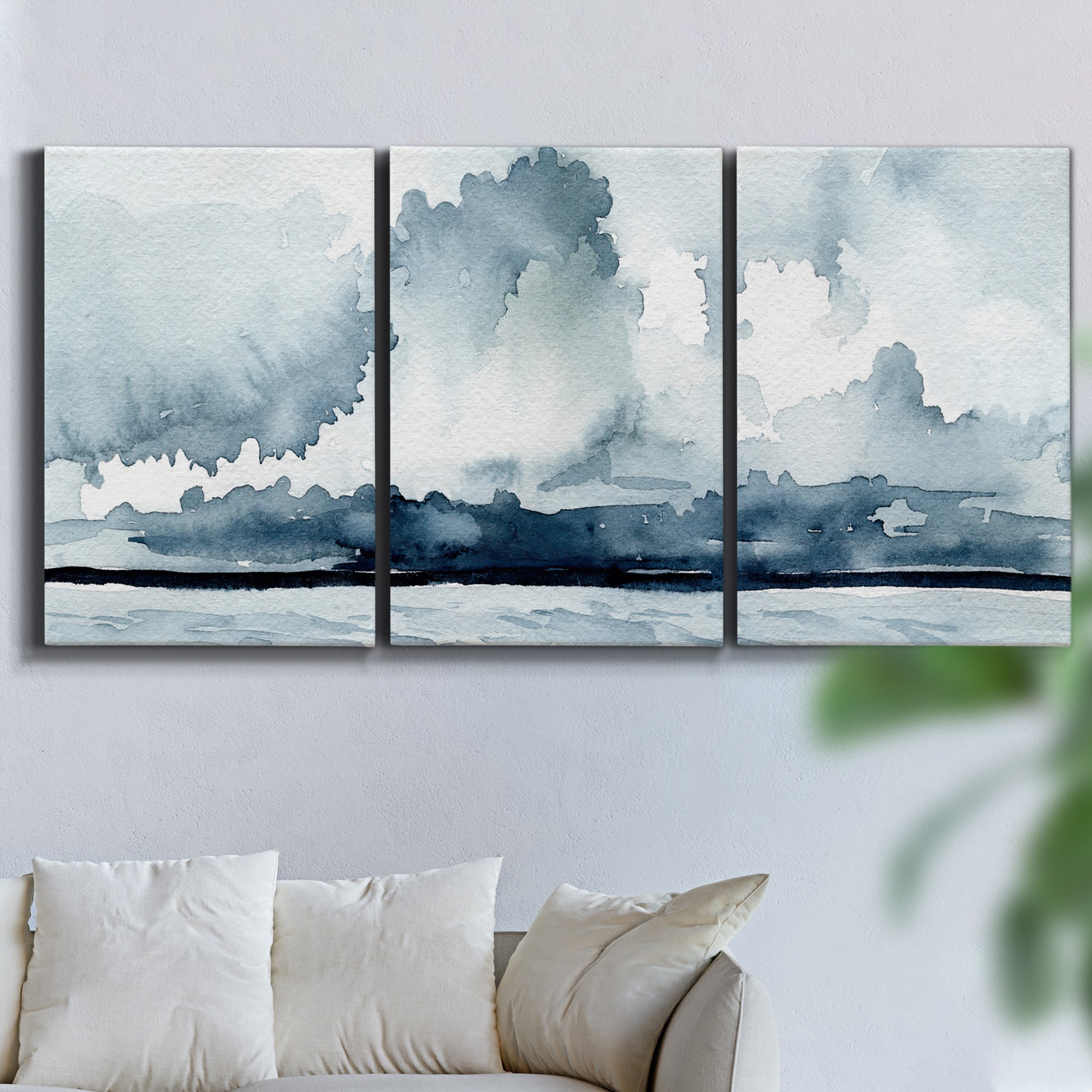 Three-panel canvas wall art featuring abstract rainstorm watercolor, displayed in a living room above a sofa.