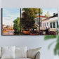 Three-panel canvas wall art featuring riverside houses along canal, displayed in a living room above a sofa.