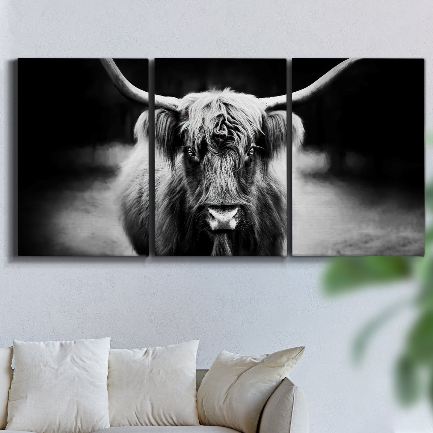 Three-panel canvas wall art featuring black and white cattle portrait, displayed in a living room above a sofa.