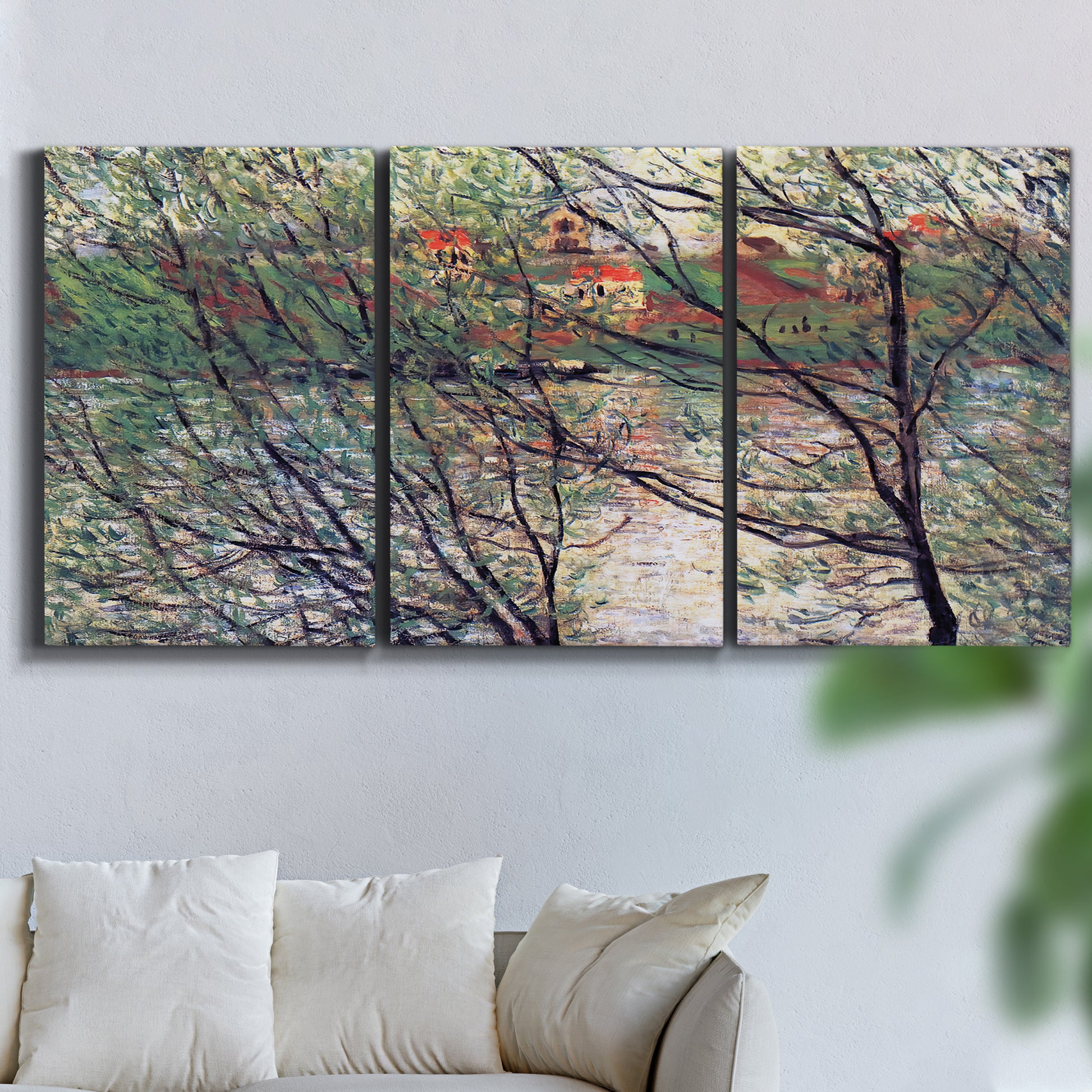 Three-panel canvas wall art featuring riverside park with figures and trees, displayed in a living room above a sofa.