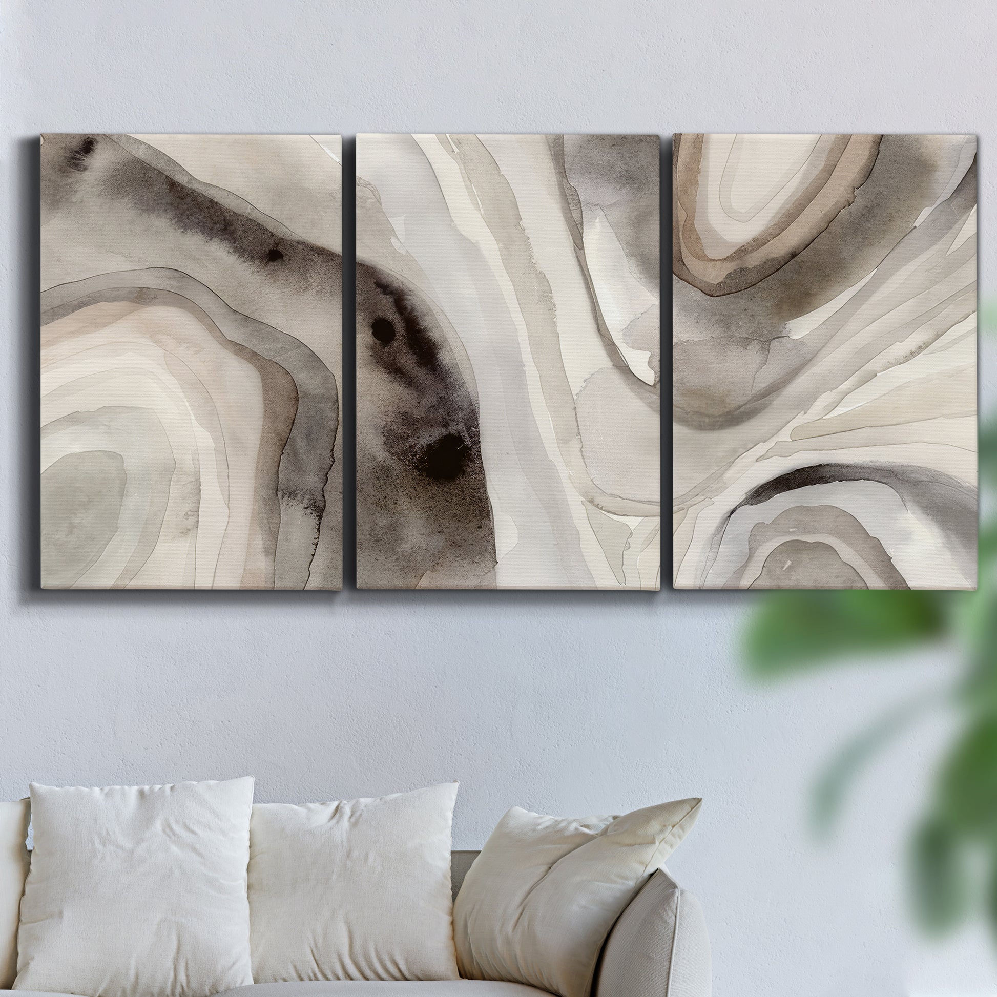 Three-panel canvas wall art featuring layered stone inspired abstract forms, displayed in a living room above a sofa.