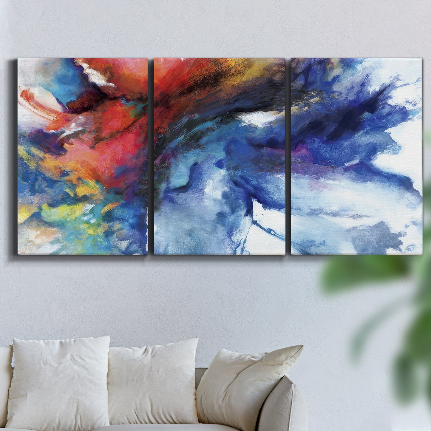 Three-panel canvas wall art featuring vibrant abstract color explosion, displayed in a living room above a sofa.