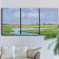 Three-panel canvas wall art featuring summer marshland with tall grasses, displayed in a living room above a sofa.