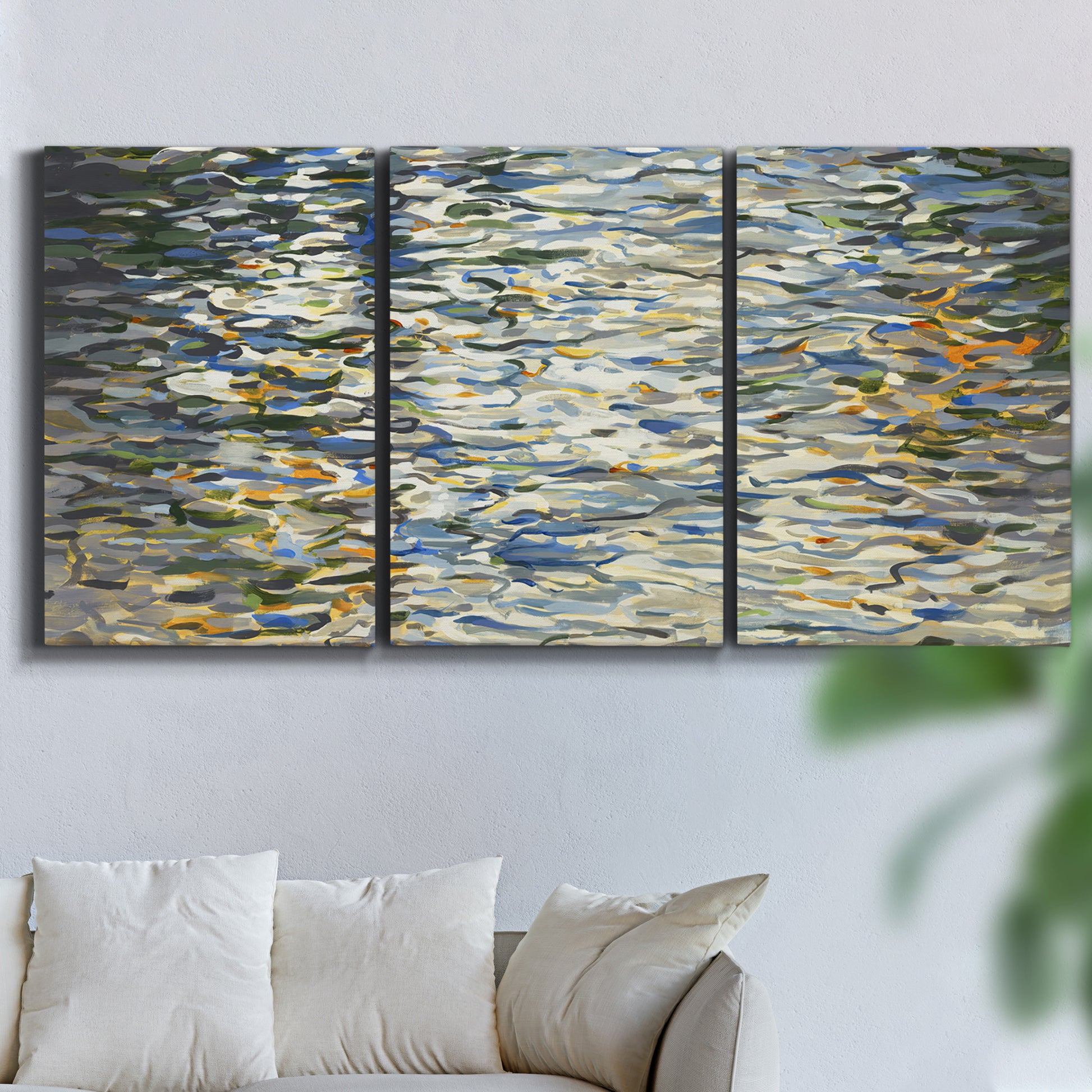 Three-panel canvas wall art featuring abstract water surface reflections, displayed in a living room above a sofa.