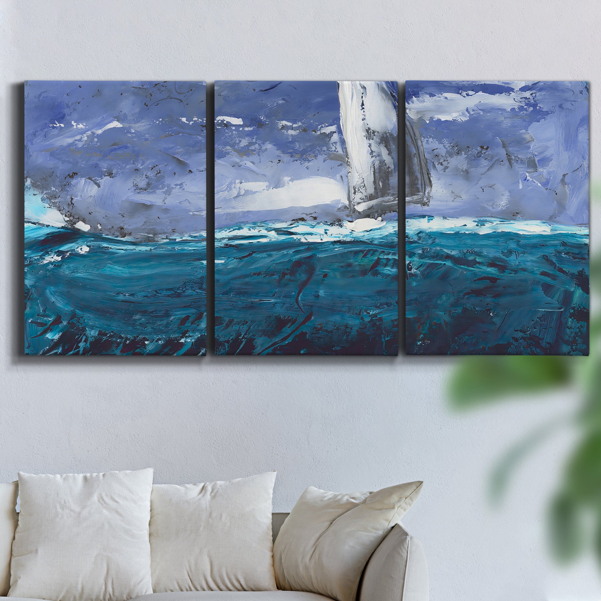 Three-panel canvas wall art featuring sailboats moving across water, displayed in a living room above a sofa.