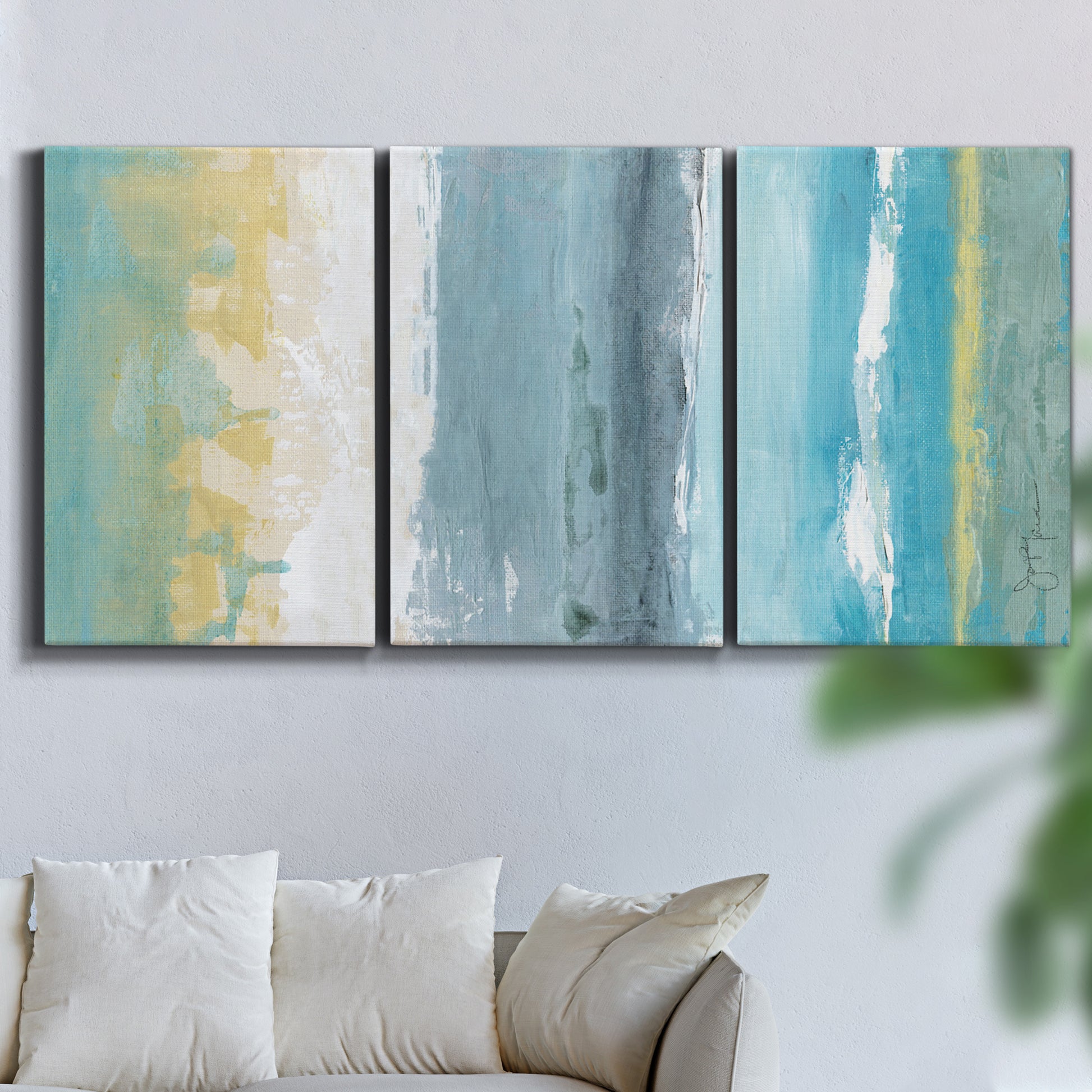 Three-panel canvas wall art featuring abstract coastal beach textures, displayed in a living room above a sofa.